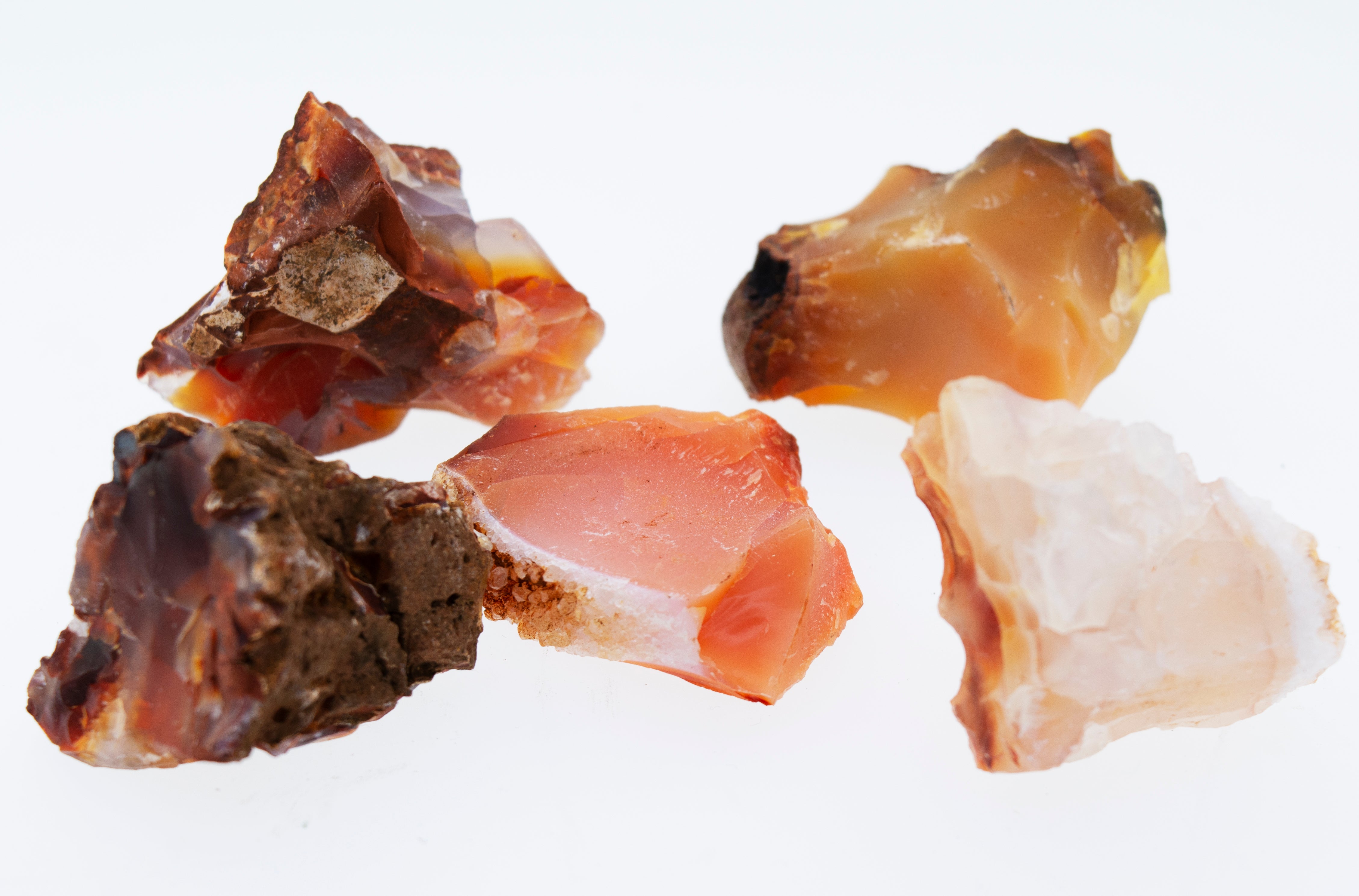 A cluster of raw carnelian crystals on a white background.