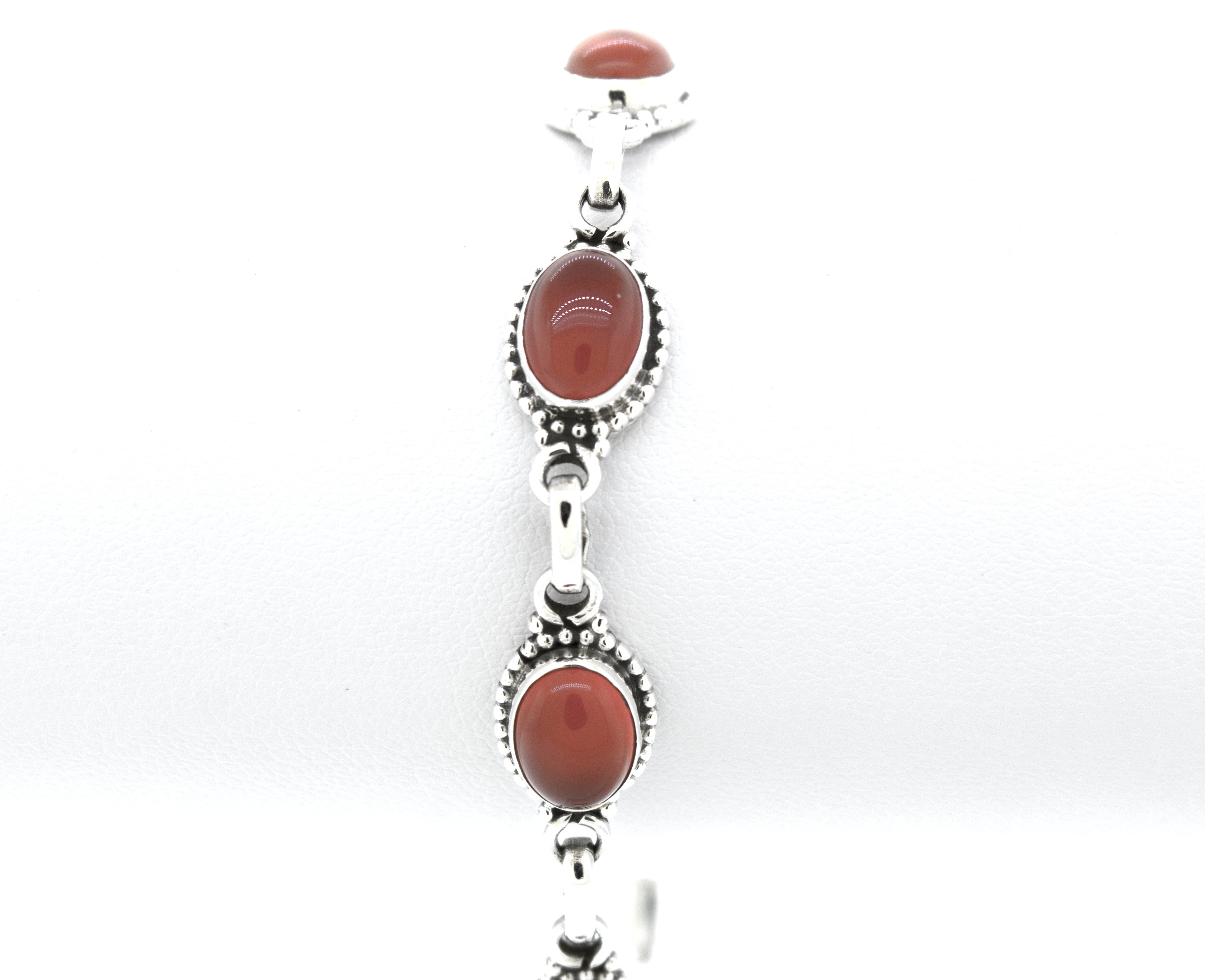 A Super Silver Oval Gemstone Bracelet With Ball Border with a red coral stone.