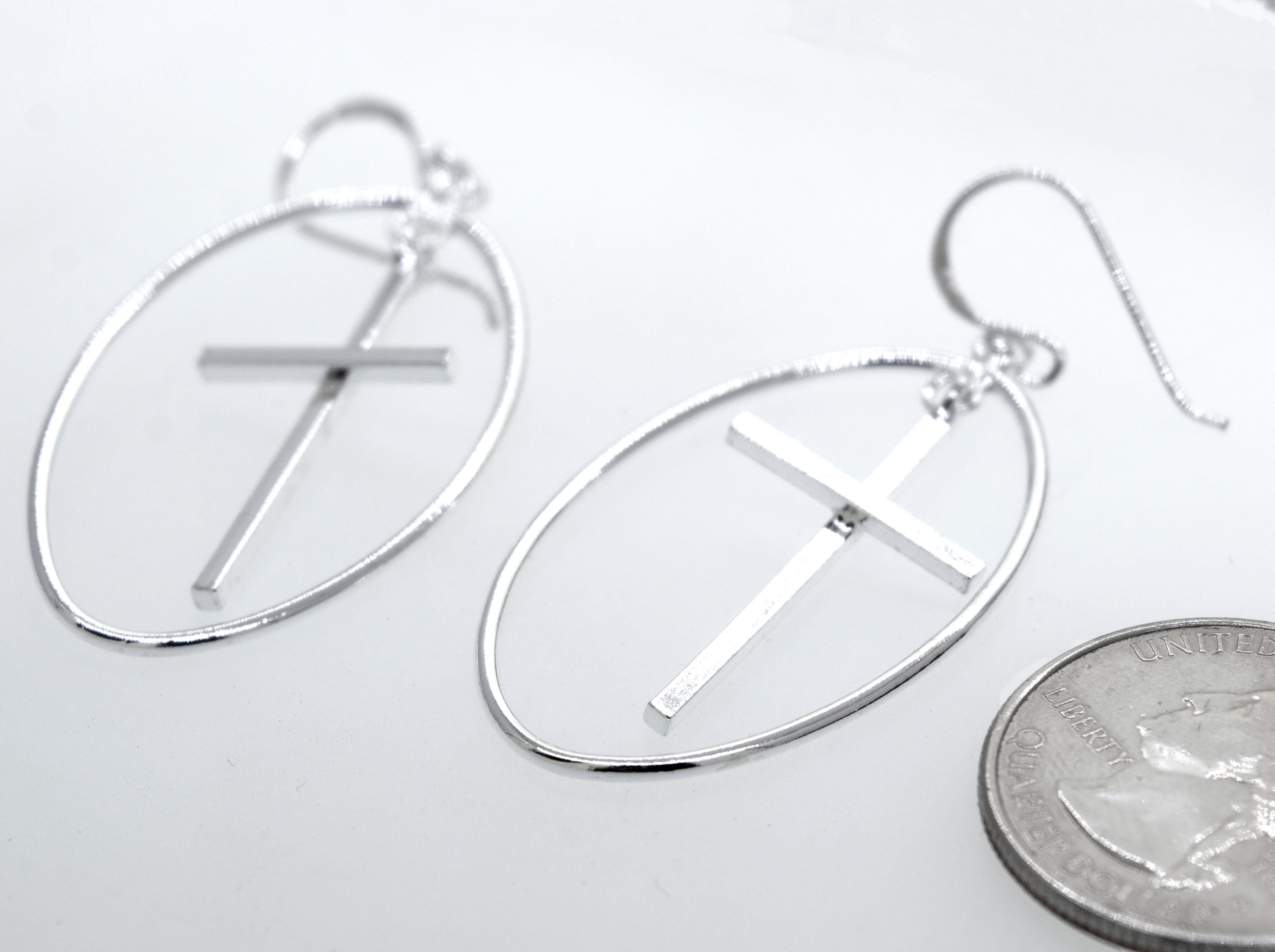 A pair of Super Silver Modern Cross Earrings with an oval wire design casing.