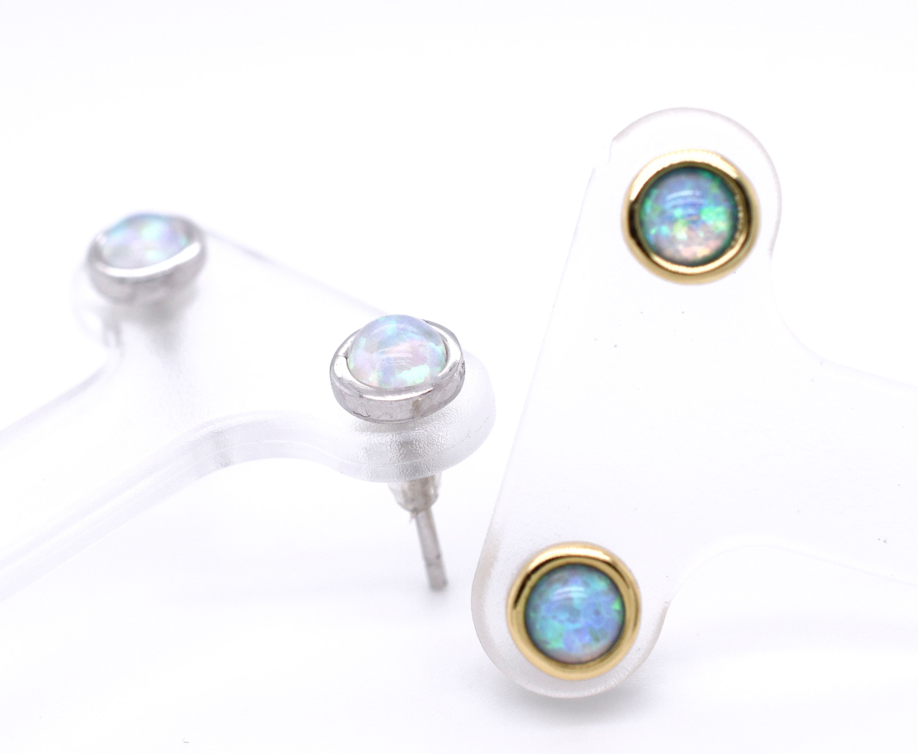 A pair of Radiant Australian Opal Studs by Super Silver, showcasing brilliant colors, on a white surface.