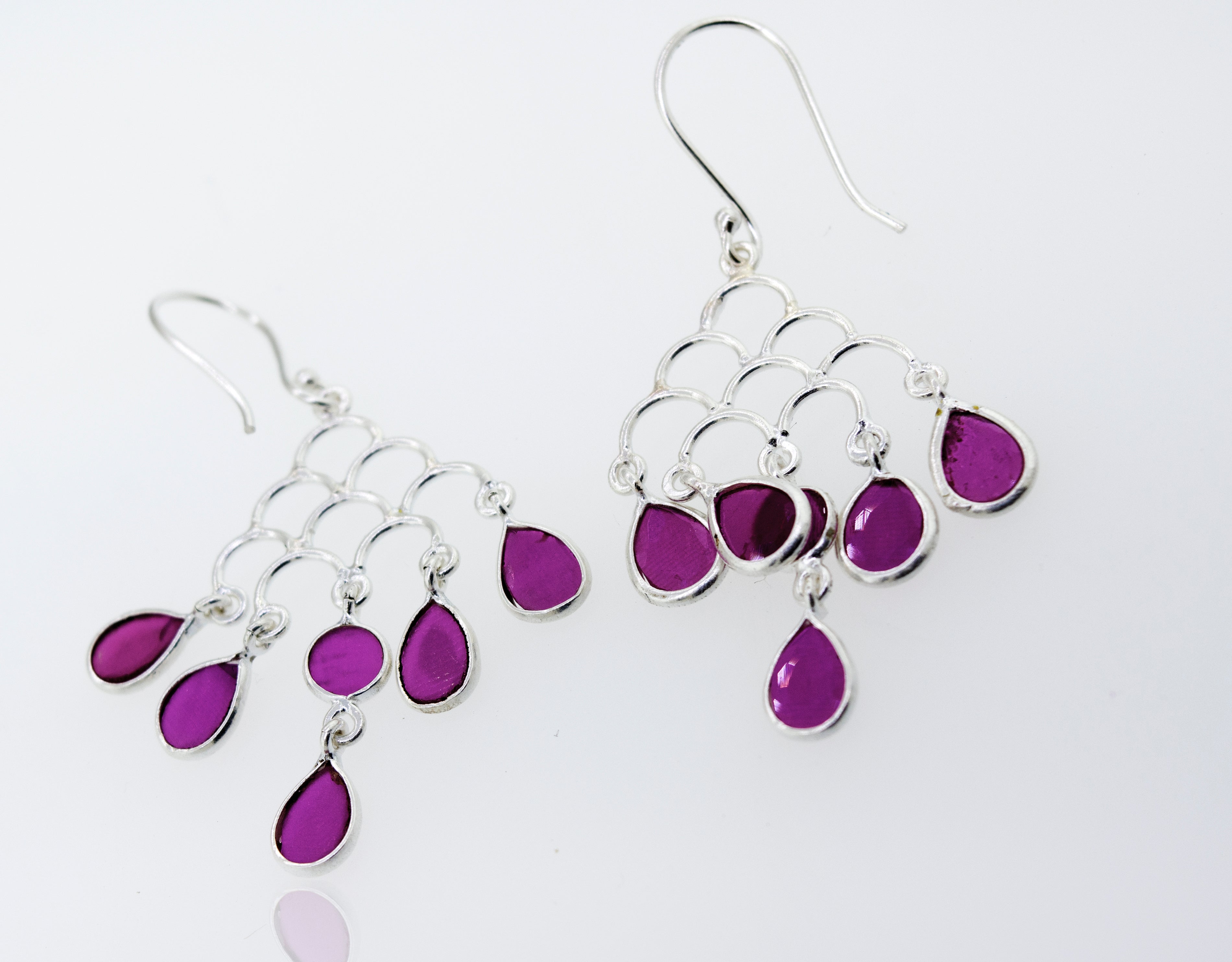 A pair of purple Faceted Ruby Chandelier Earrings by Super Silver on a white surface.