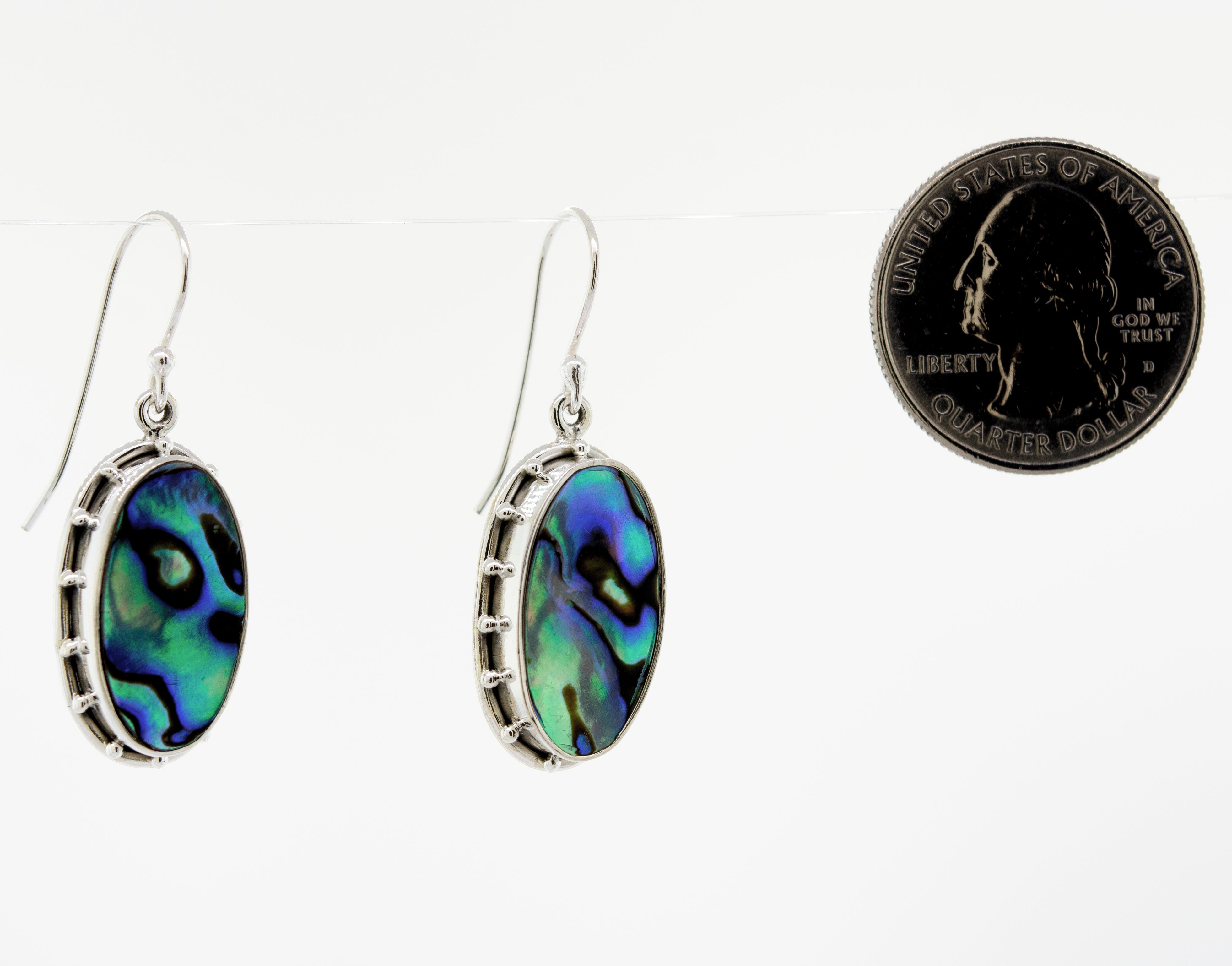 A pair of Super Silver Oval Abalone Earrings with a decorative border, crafted from 925 sterling silver, placed next to a quarter.