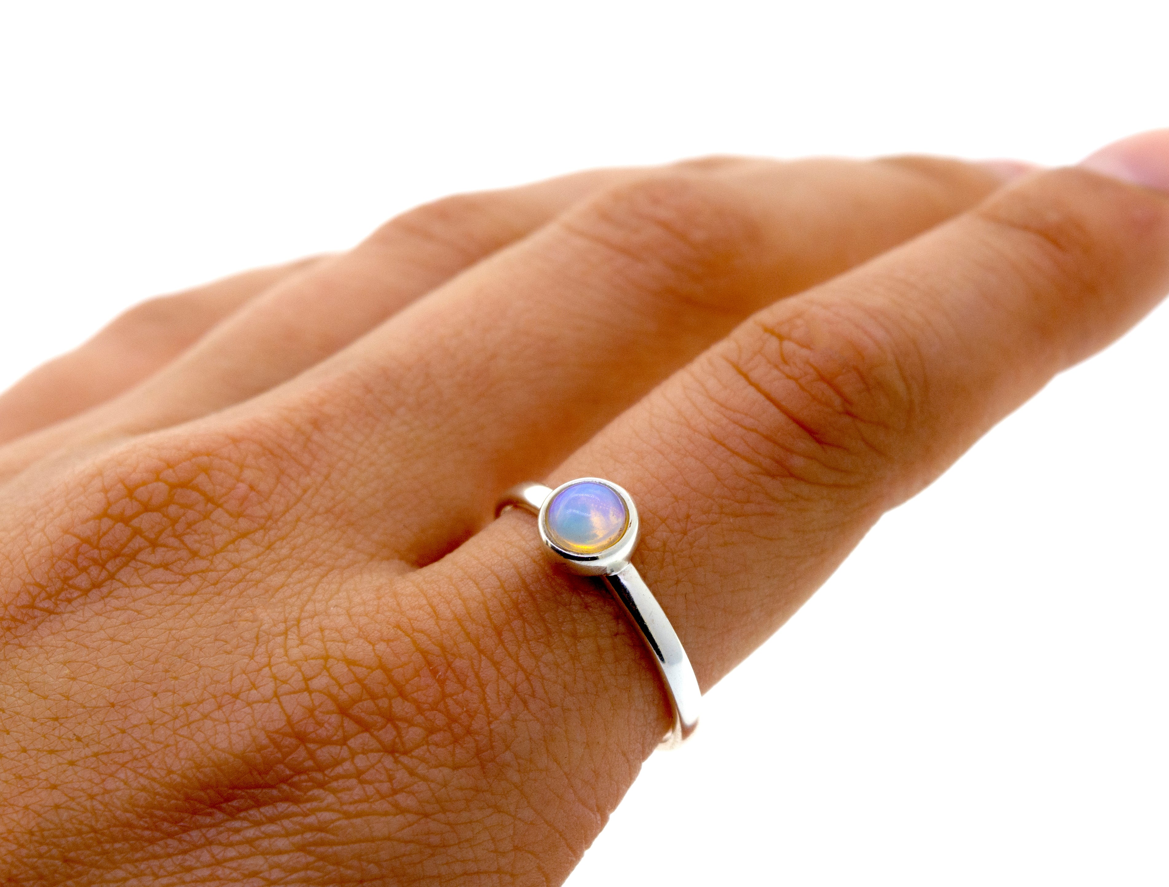 An elegant woman's hand holding a statement Glowing Ethiopian Opal Ring.