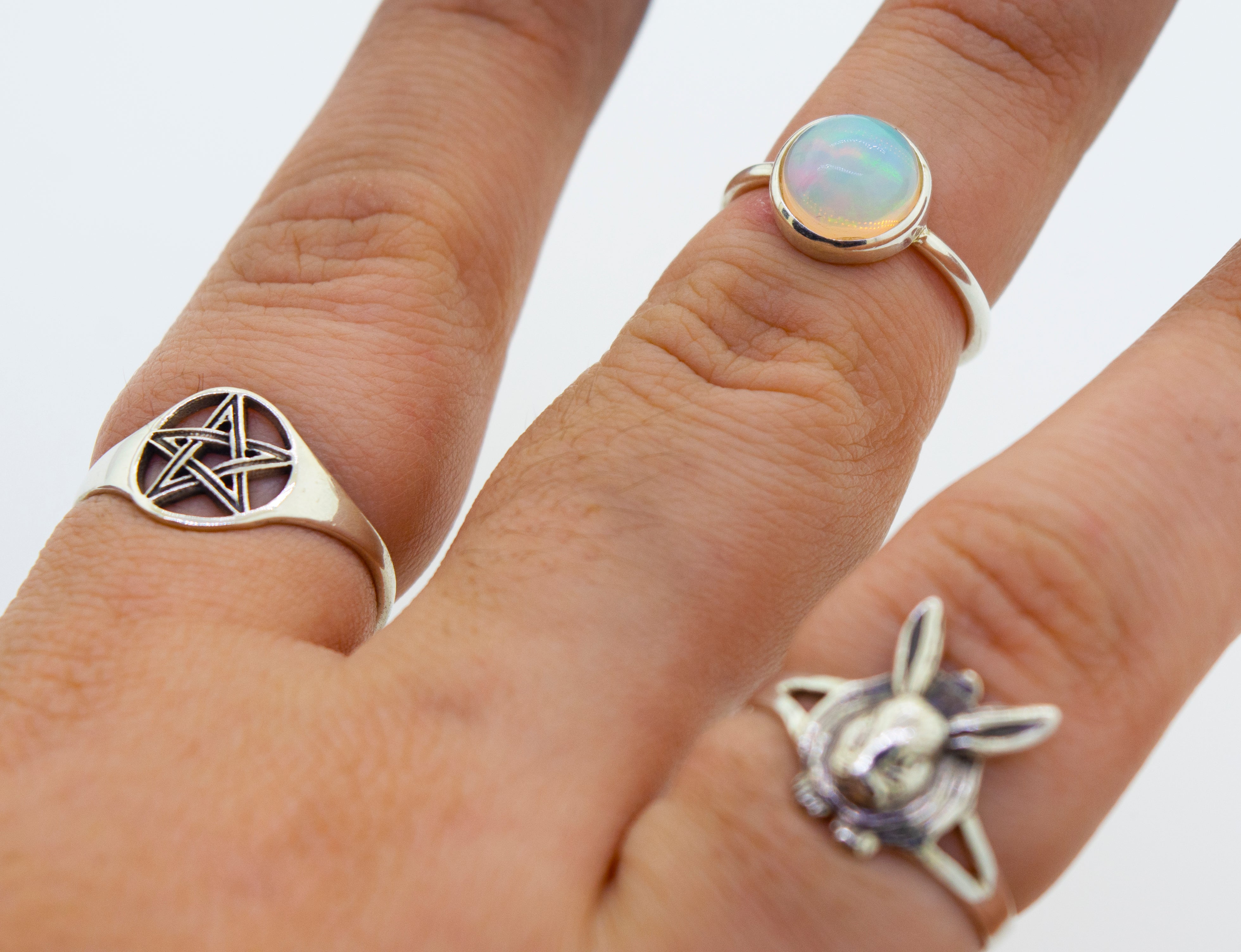 An elegant woman's hand adorned with three Round Ethiopian Opal Rings, making a stunning statement.