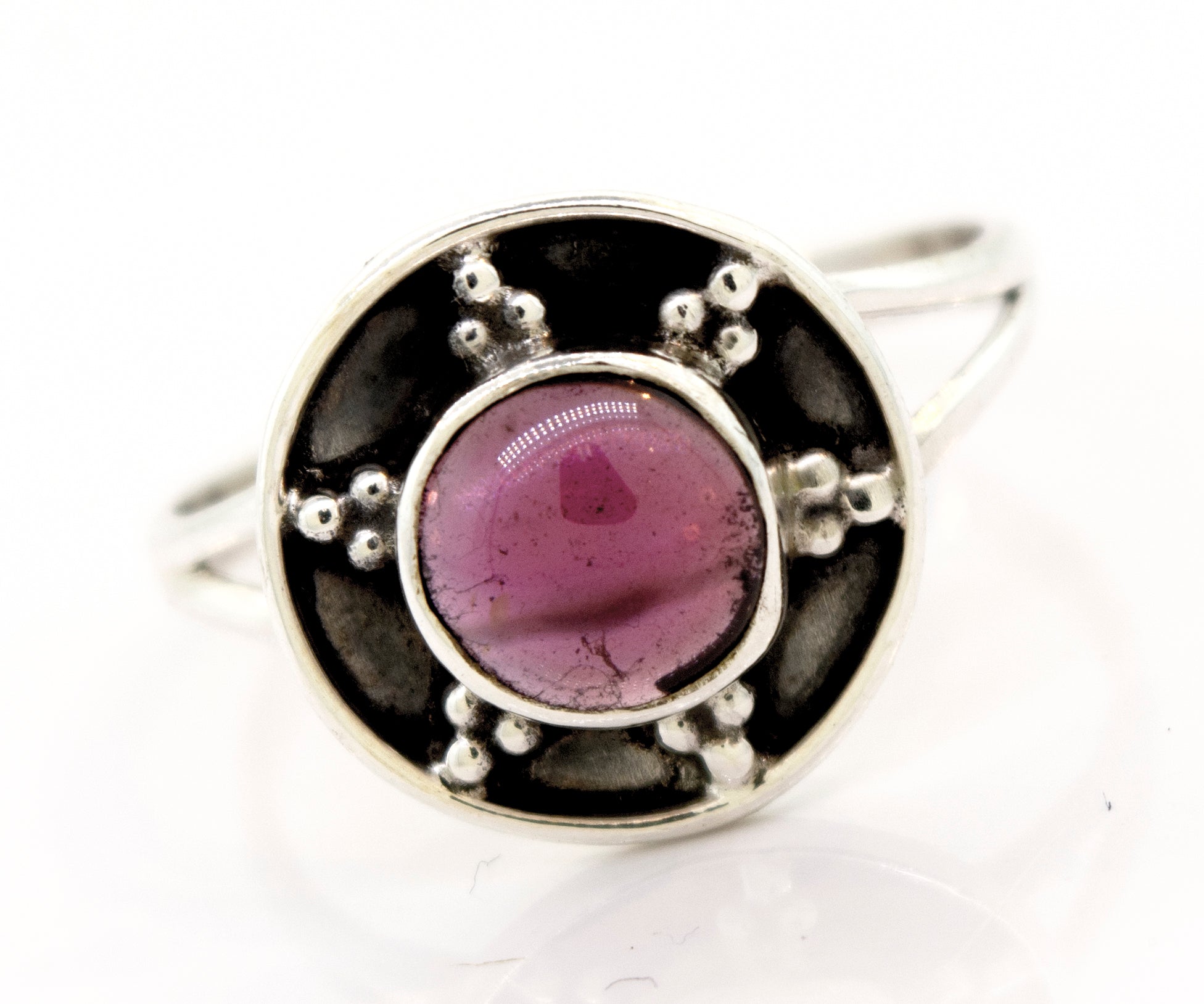 A Super Silver garnet ring with a unique oxidized silver design, featuring a pink stone in the center and an oxidized silver shield design.