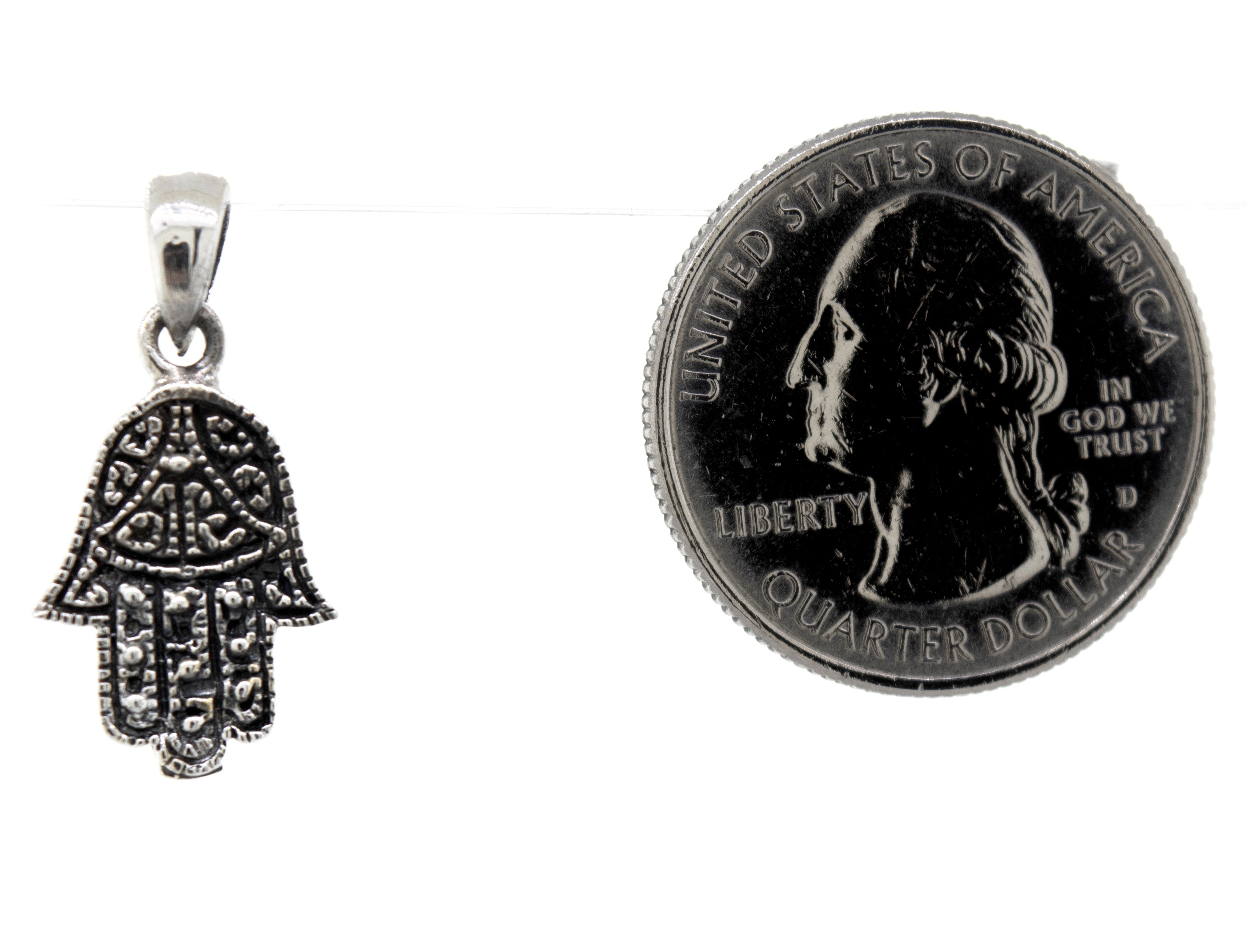 A Super Silver small Hamsa hand pendant made of sterling silver next to a dime.