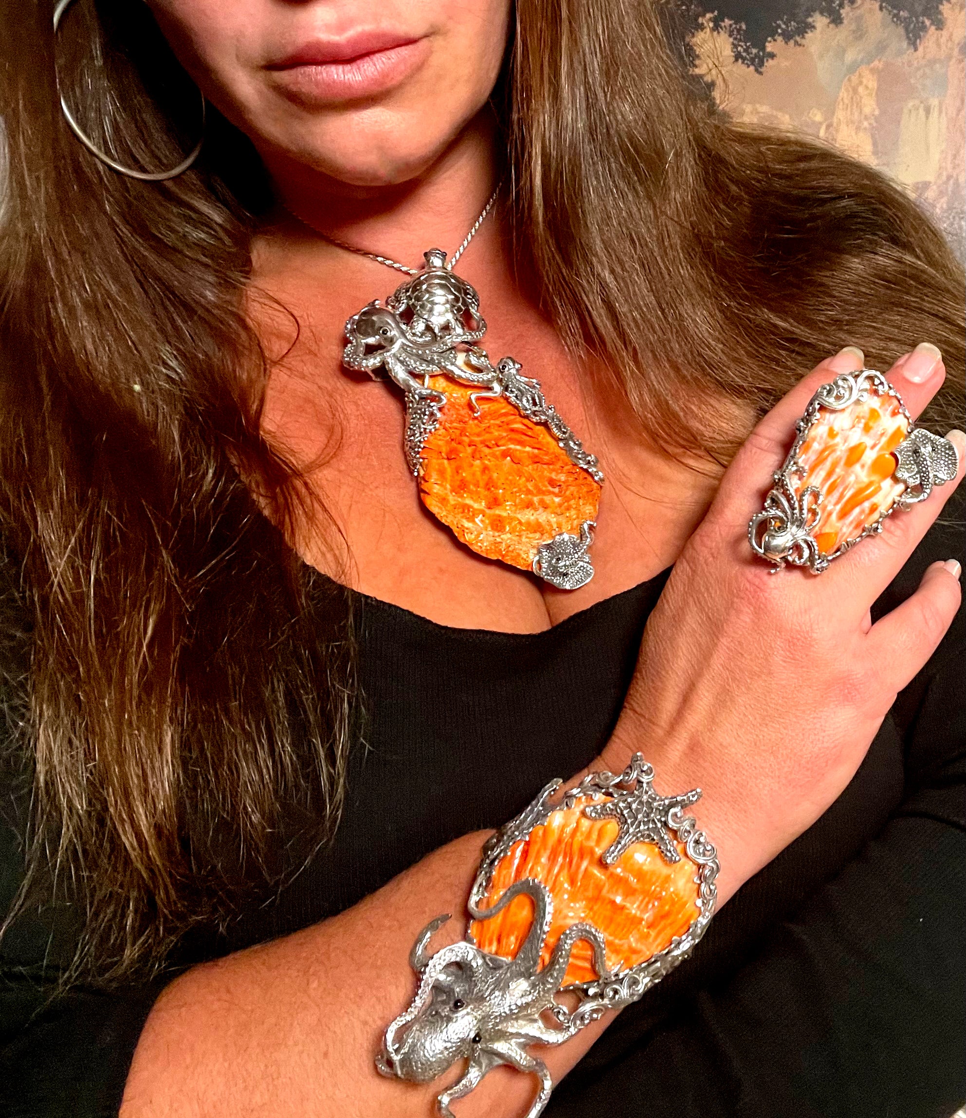 A woman wearing an orange octopus ring with a Super Silver Handcrafted Spiny Shell Designer Cuff Bracelet.