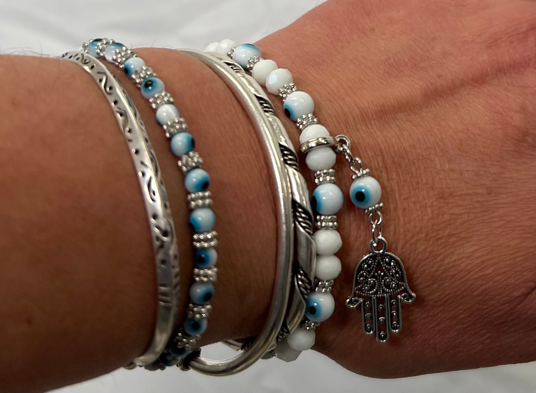 A woman is wearing a Super Silver Evil Eye Stretch bracelet with Hamsa Charm.