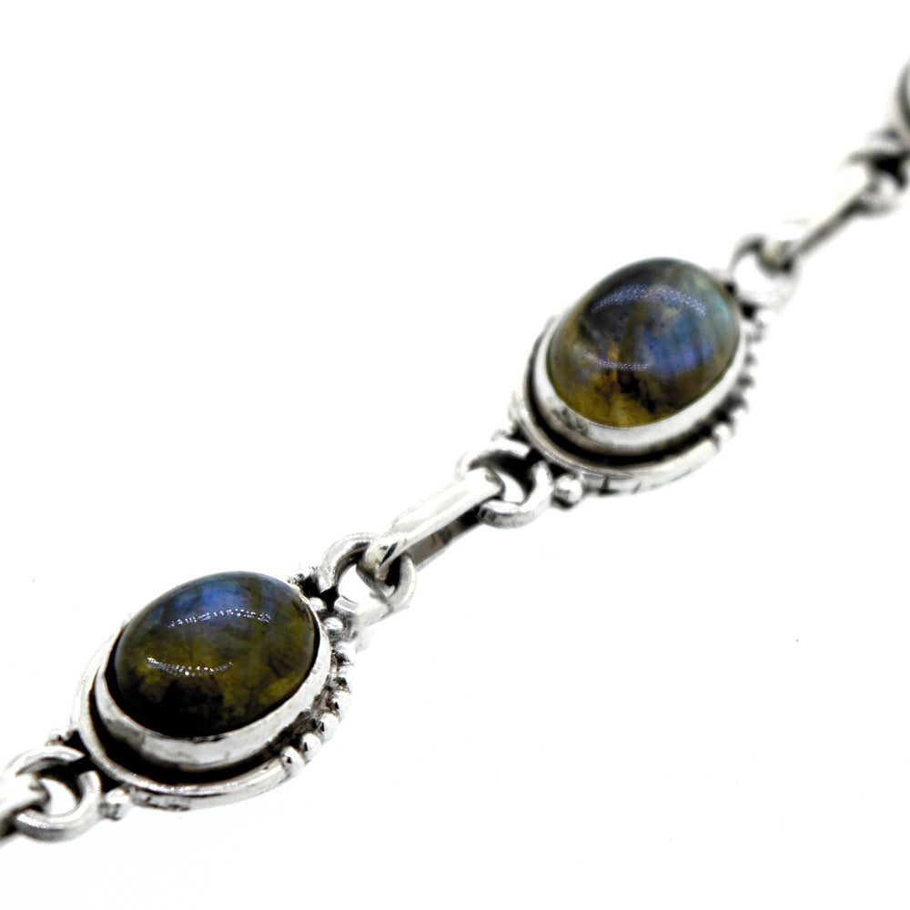 
                  
                    A Super Silver Oval Gemstone Bracelet with Half Ball Border adorned with labradorite stones.
                  
                