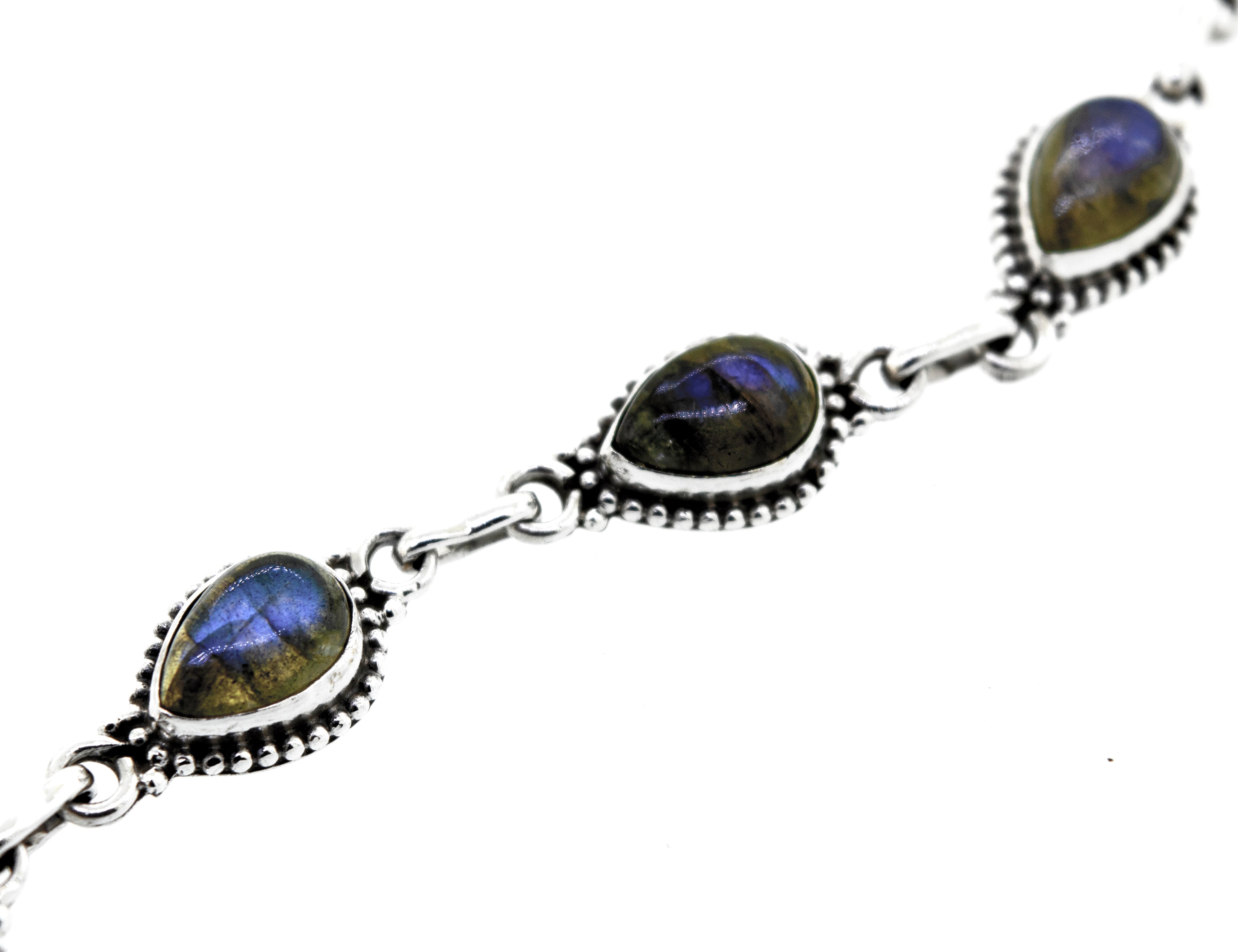 A Teardrop Shape Stone Bracelet With Ball Border crafted from .925 silver, featuring five teardrop-shaped gemstones with a captivating blue iridescent sheen.