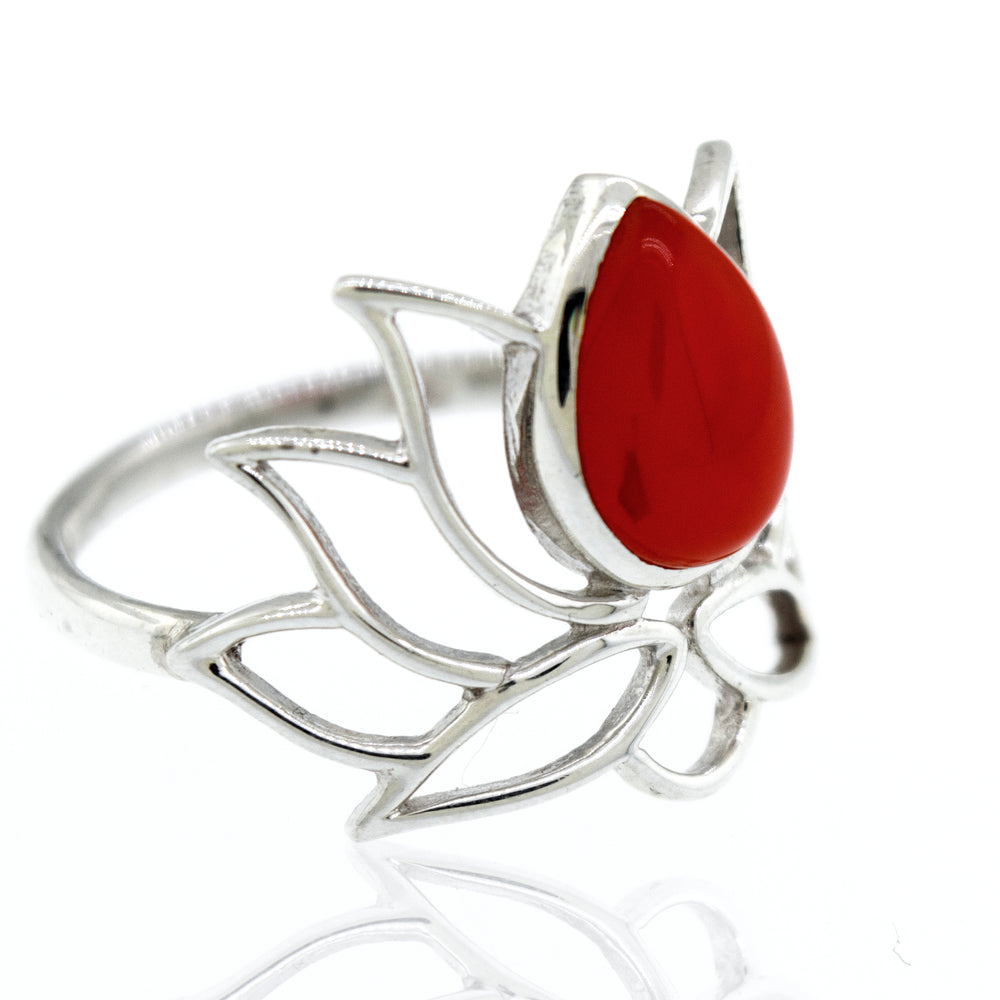 
                  
                    Online Exclusive Teardrop Stone Lotus Ring with an intricate leaf design and a large, teardrop-shaped red gemstone set in the center, displayed on a reflective surface.
                  
                