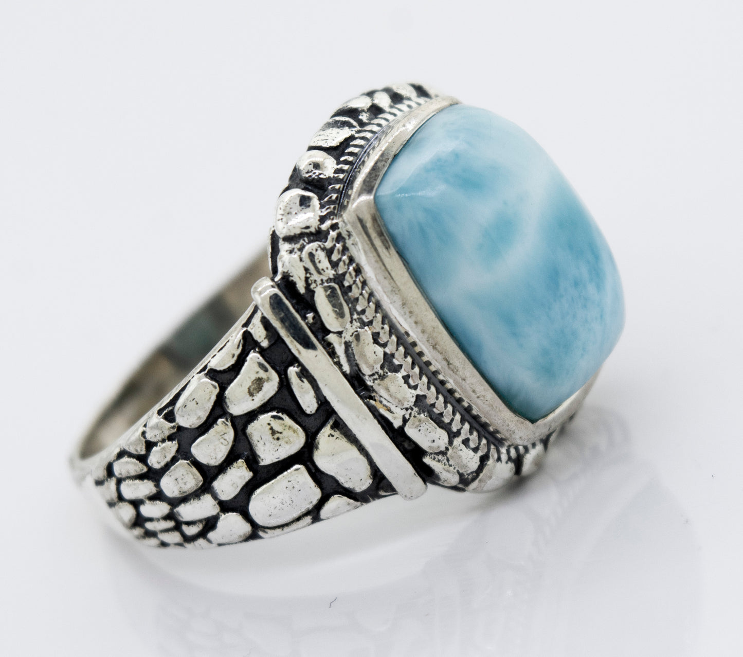 A Larimar Signet Ring With Dragon Scale Pattern with a blue stone.