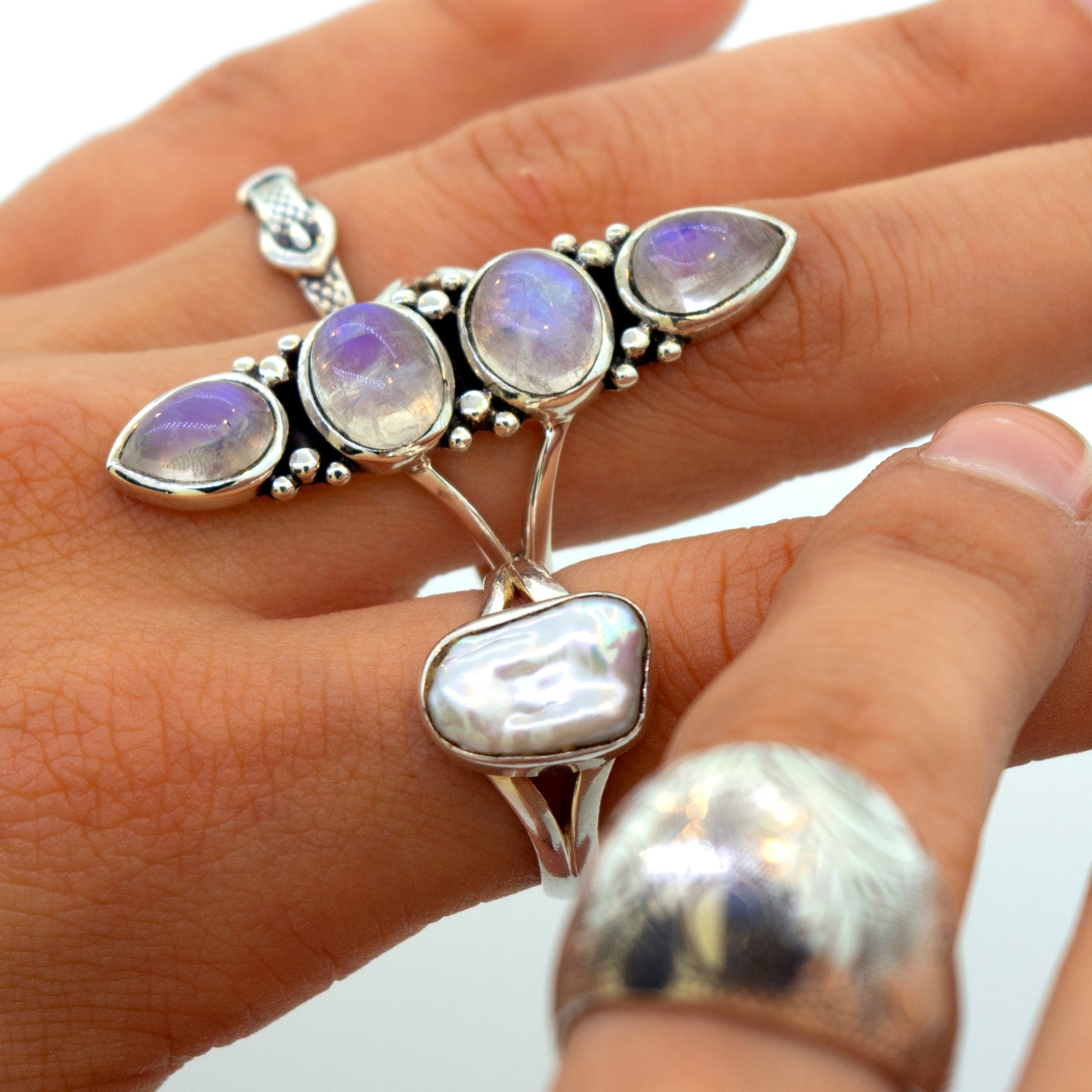 A woman's hand holding a Super Silver Online Only Exclusive Elongated Moonstone Ring adorned with opals and pearls, available at our online store.