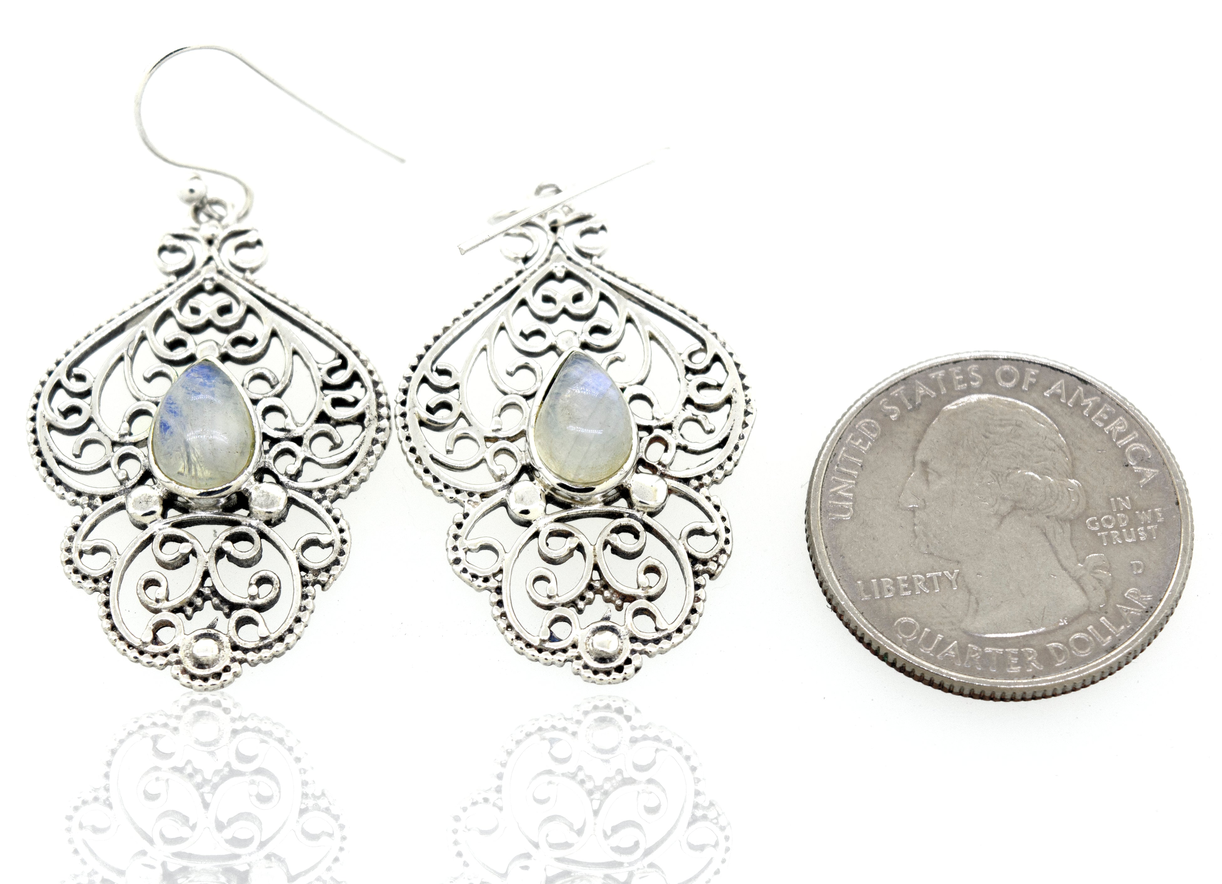 A pair of Teardrop Moonstone Earrings With Freestyle Silver Design next to them.