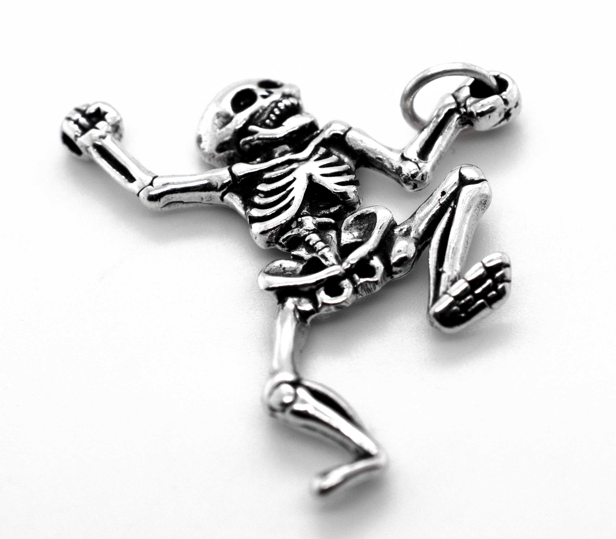 The Dancing Skeleton Pendant is crafted from sterling silver, featuring detailed bones, bent limbs, and a top right loop for a chain—ideal as a unique Halloween necklace and shown on a white background.