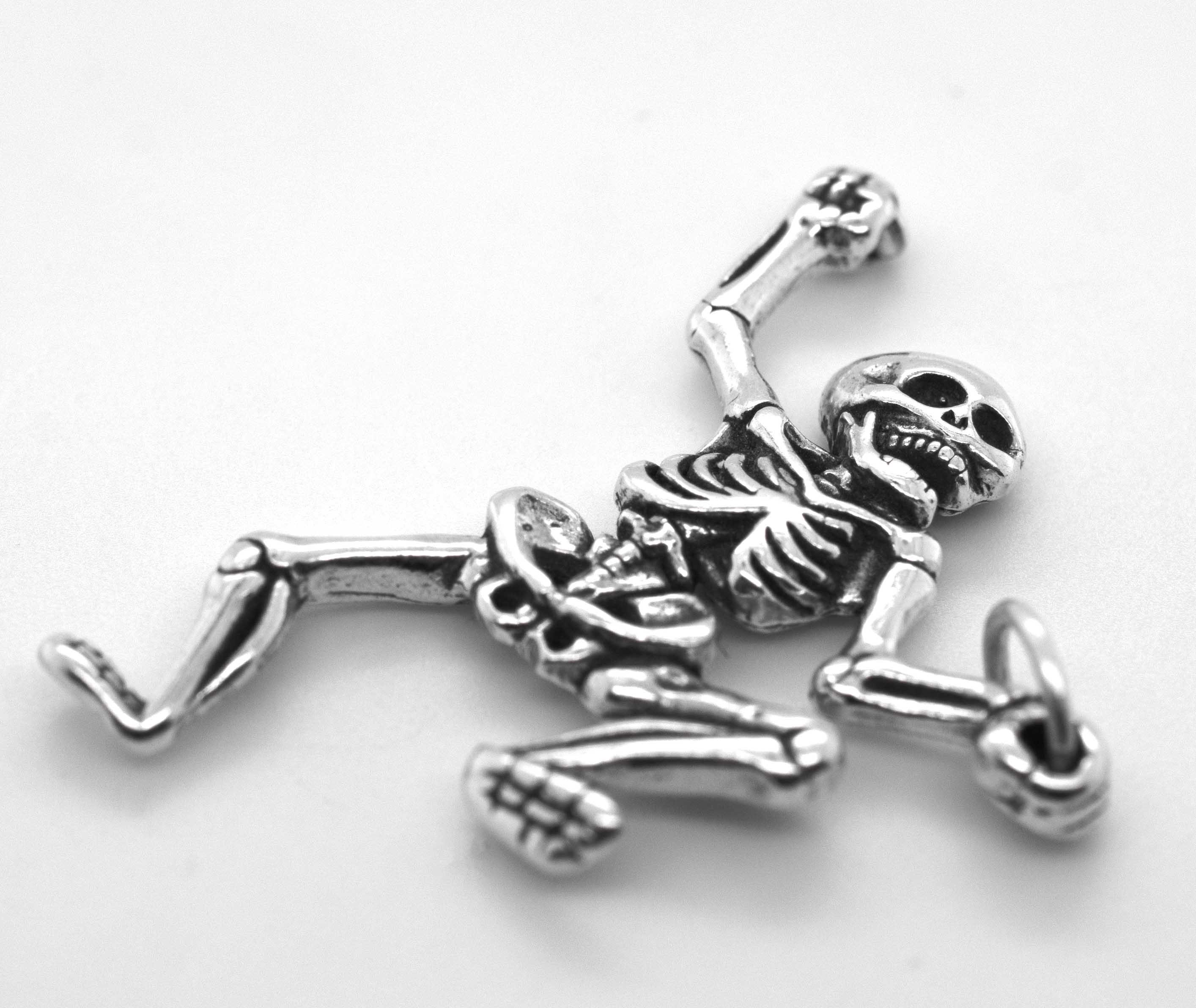 The Dancing Skeleton Pendant is a sterling silver necklace featuring a skeleton lying on its back with one arm and one leg raised—an ideal quirky accessory for Halloween.