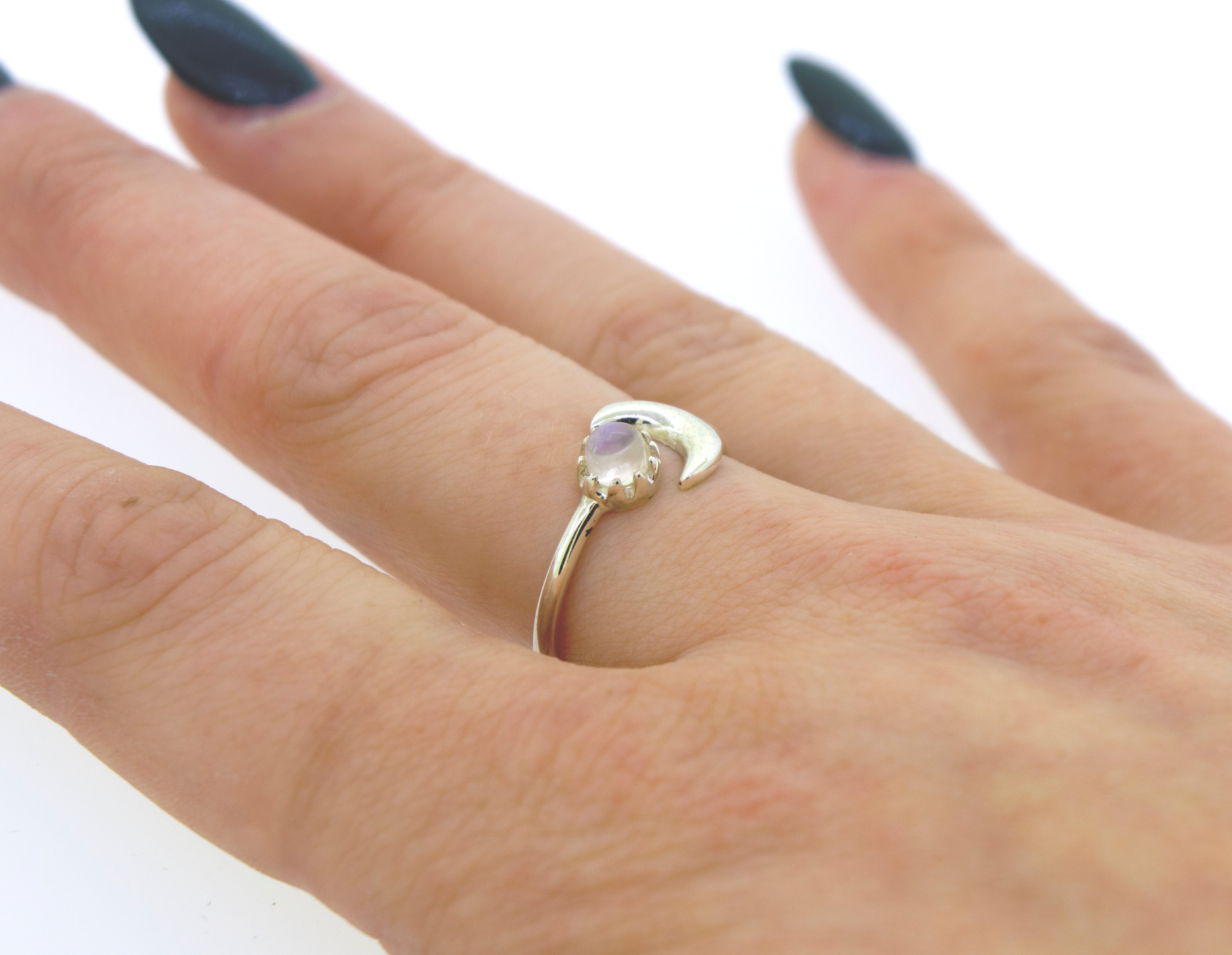 Close-up of a hand wearing an Online Exclusive Adjustable Gemstone Ring With Moon Design on the ring finger, against a white background.