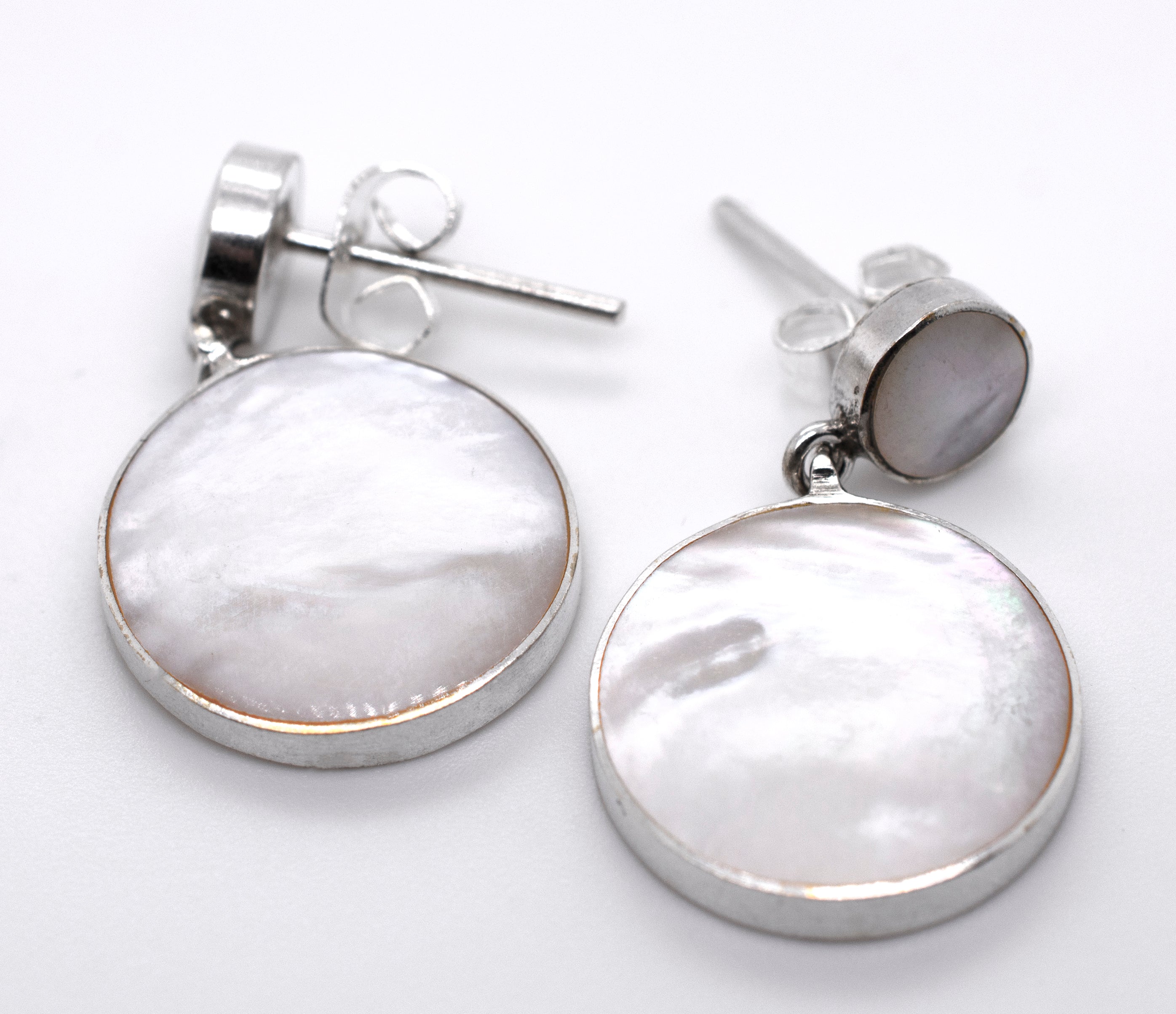 A pair of Super Silver Round Mother Of Pearl Earrings With Post on a white surface.