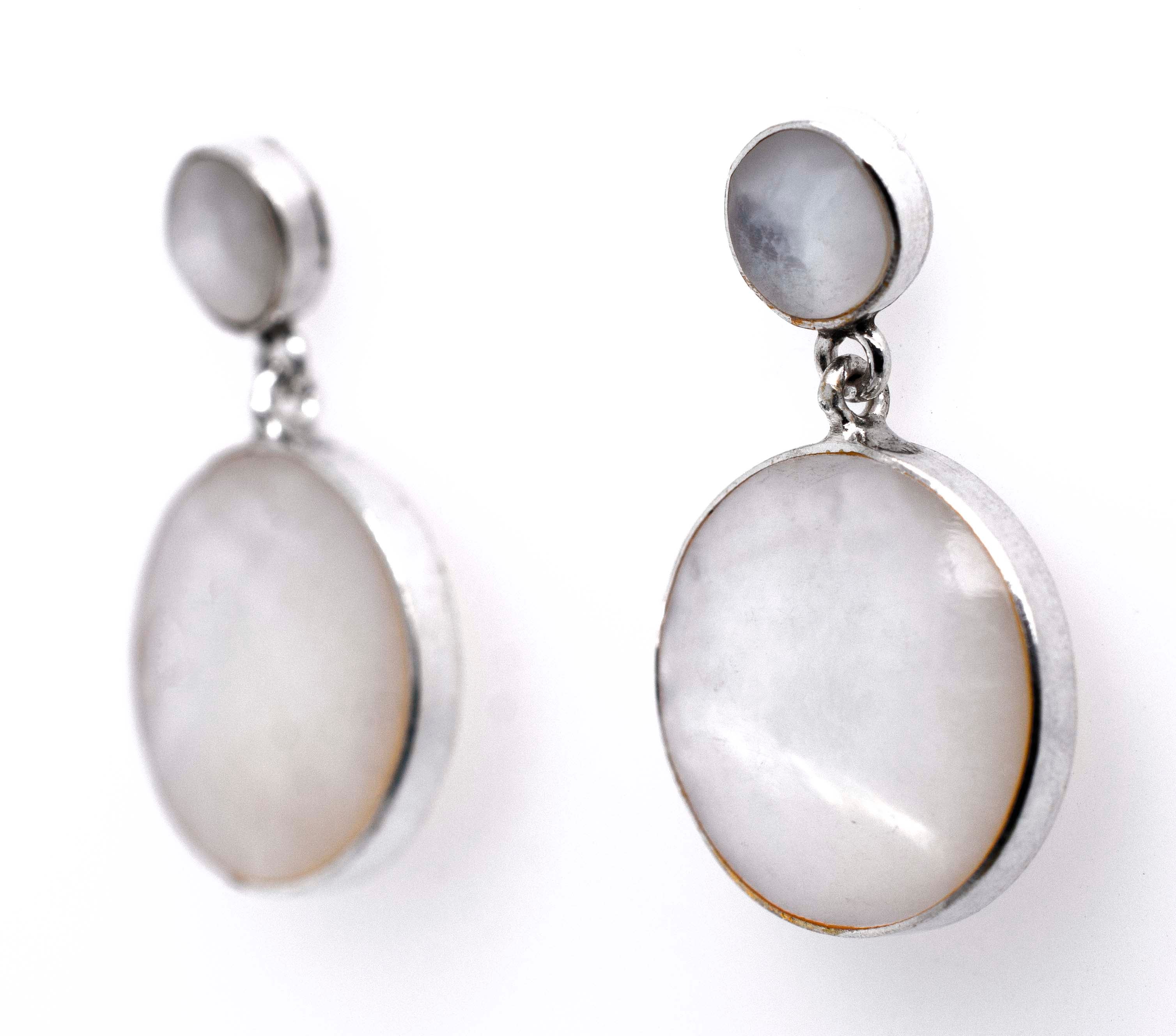 A pair of Super Silver Round Mother Of Pearl earrings showcasing exquisite refinement on a timeless white background.