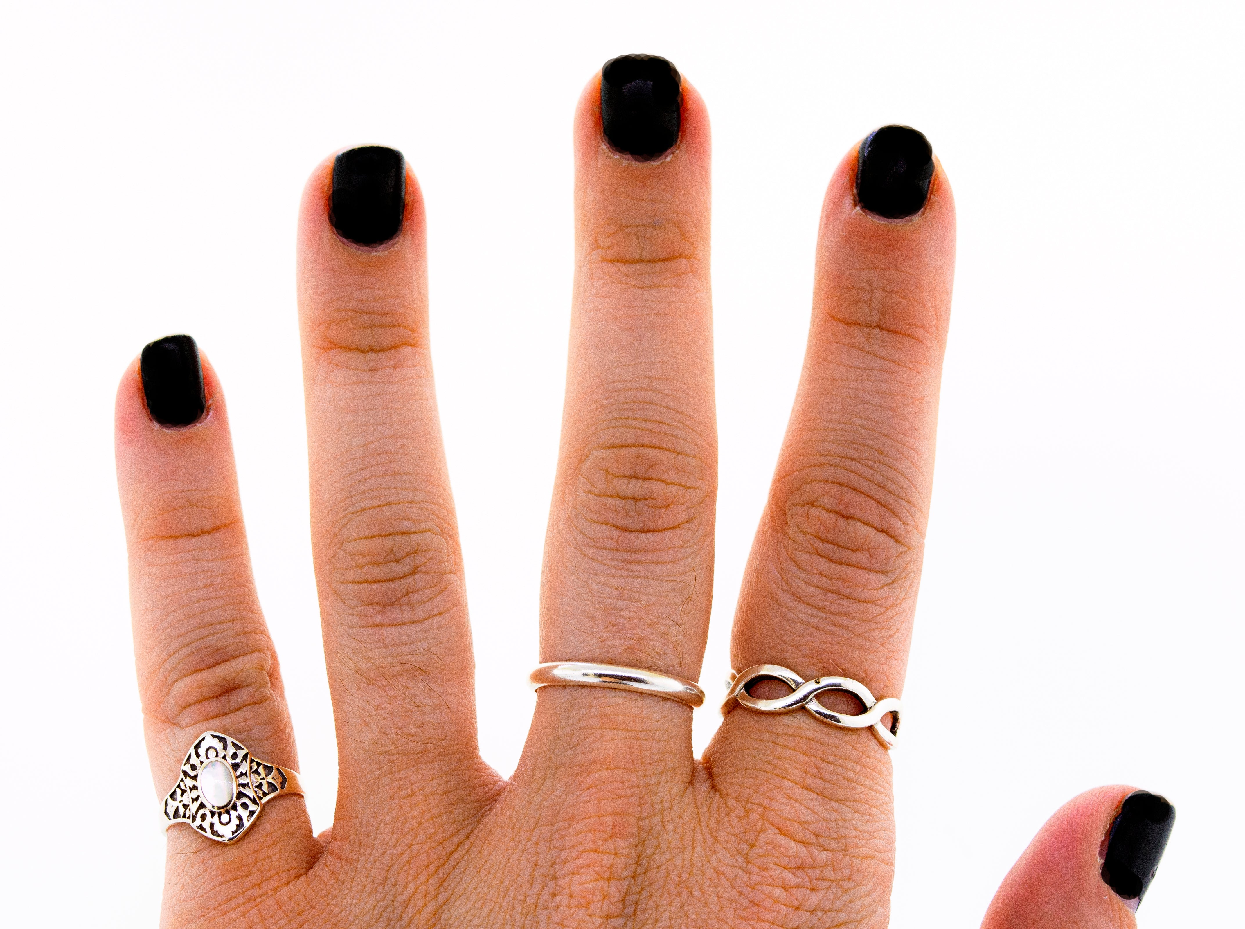 A woman's hand adorned with black nails inlaid with a Super Silver Marquise Shield Ring With Inlaid Stones.