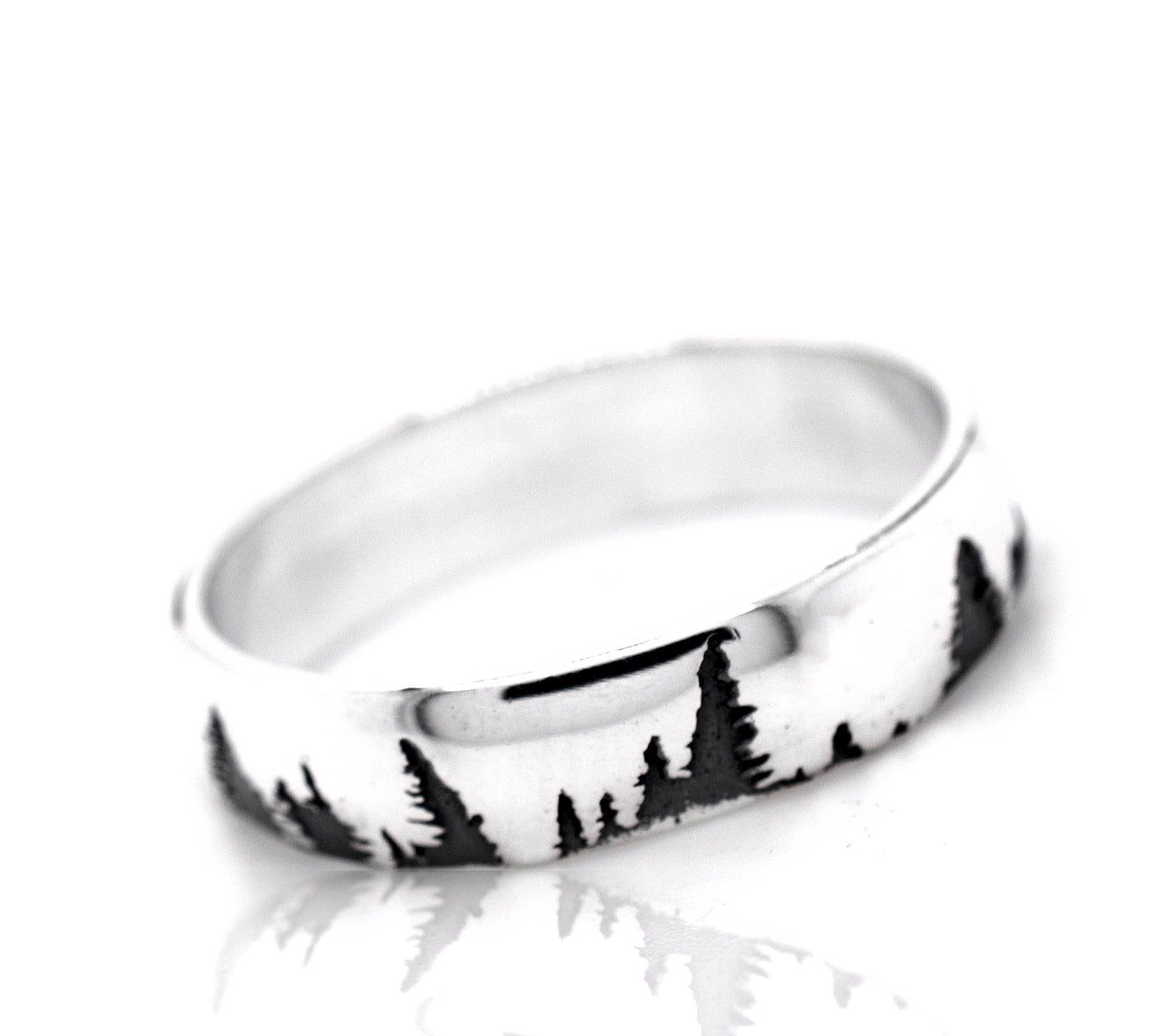 A nature-inspired sterling silver ring, the Sleek Tree Band, with trees in the background.