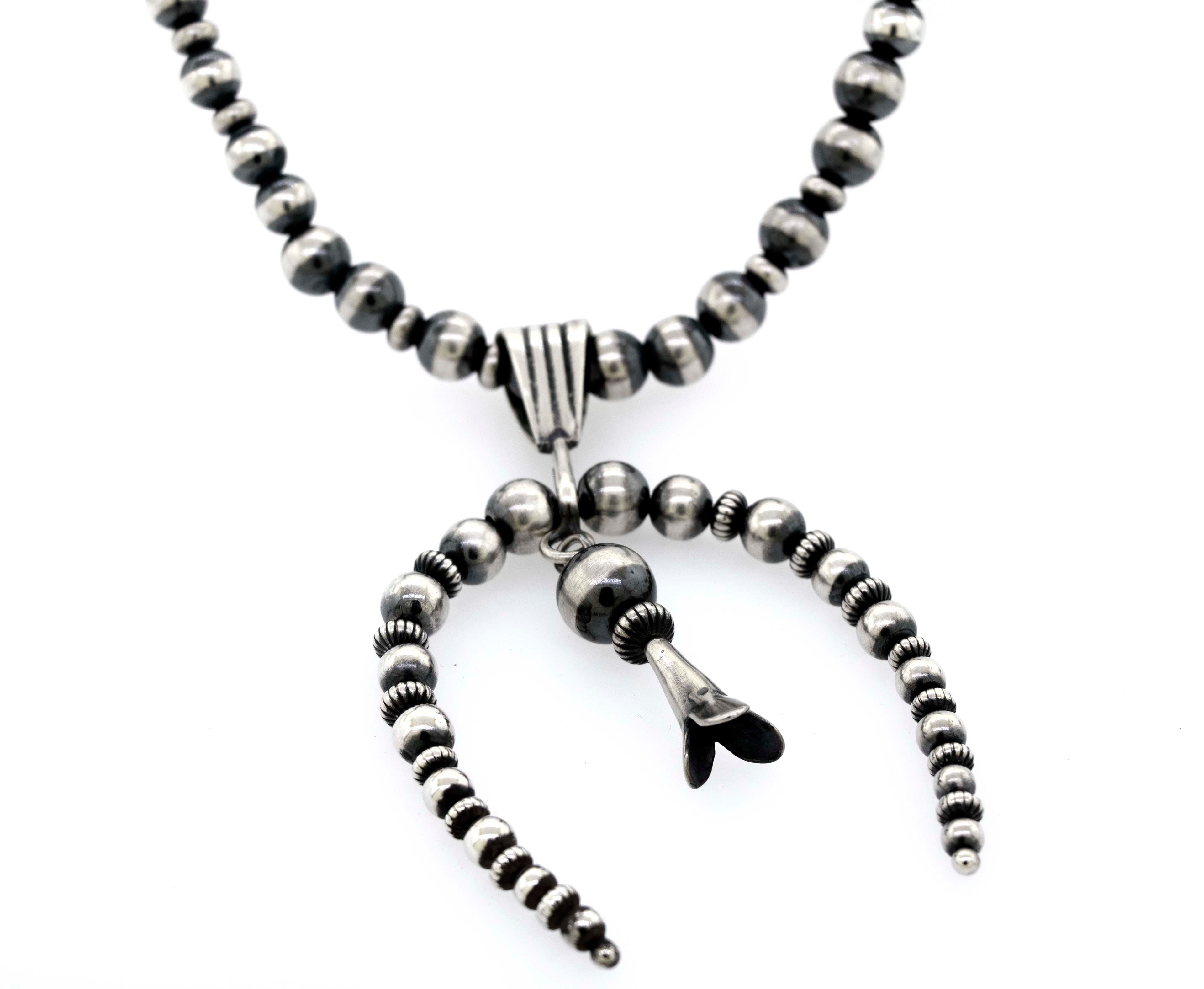 A Super Silver Handcrafted Naja Beaded Necklace adorned with black and white Navajo pearls, offering a sense of protection.