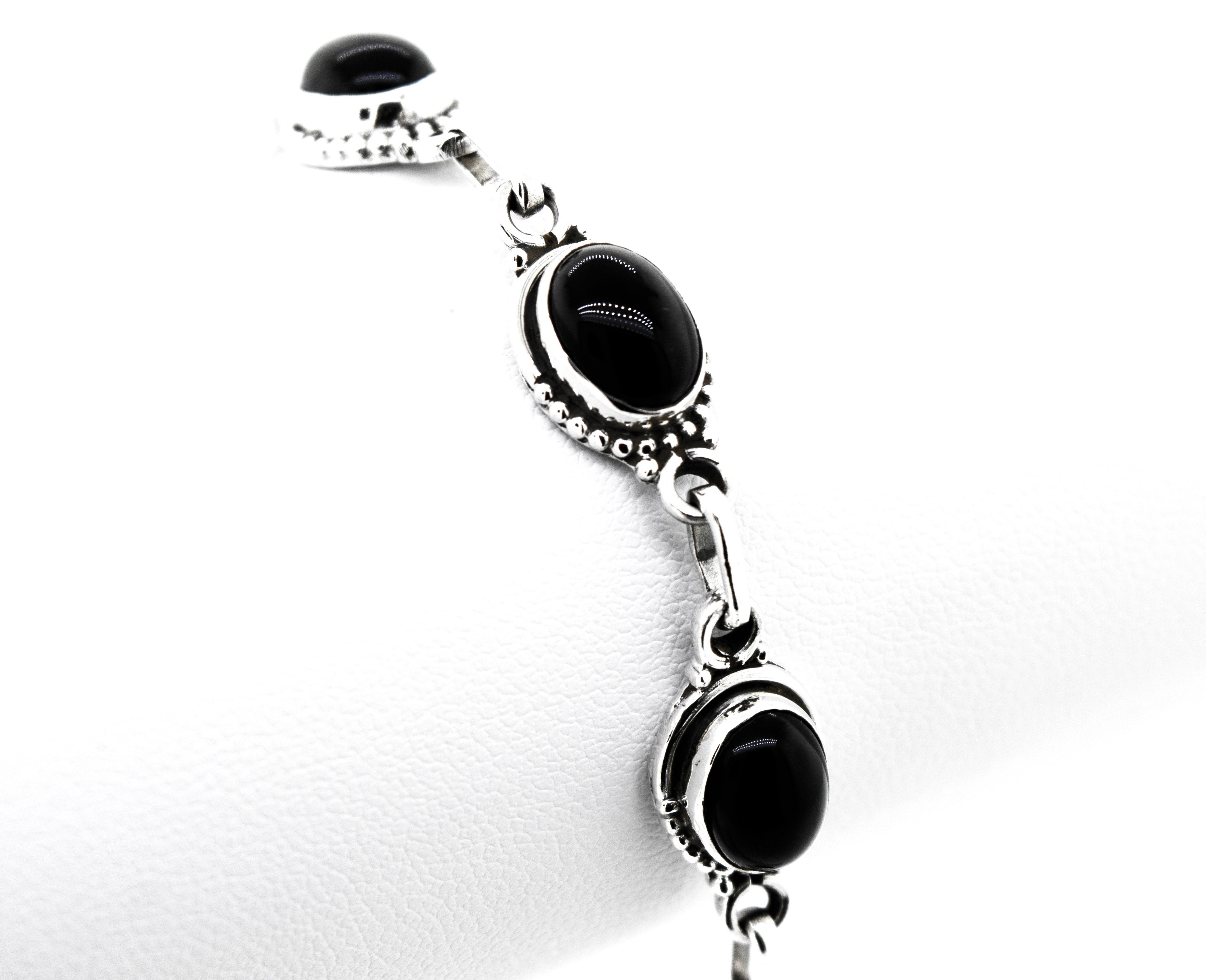 A Super Silver Oval Gemstone Bracelet with black onyx stones, perfect for a bohemian chic look.