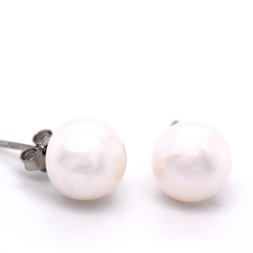 A pair of Super Silver Classic Pearl Stud Earrings with a vintage charm on a subdued white surface.