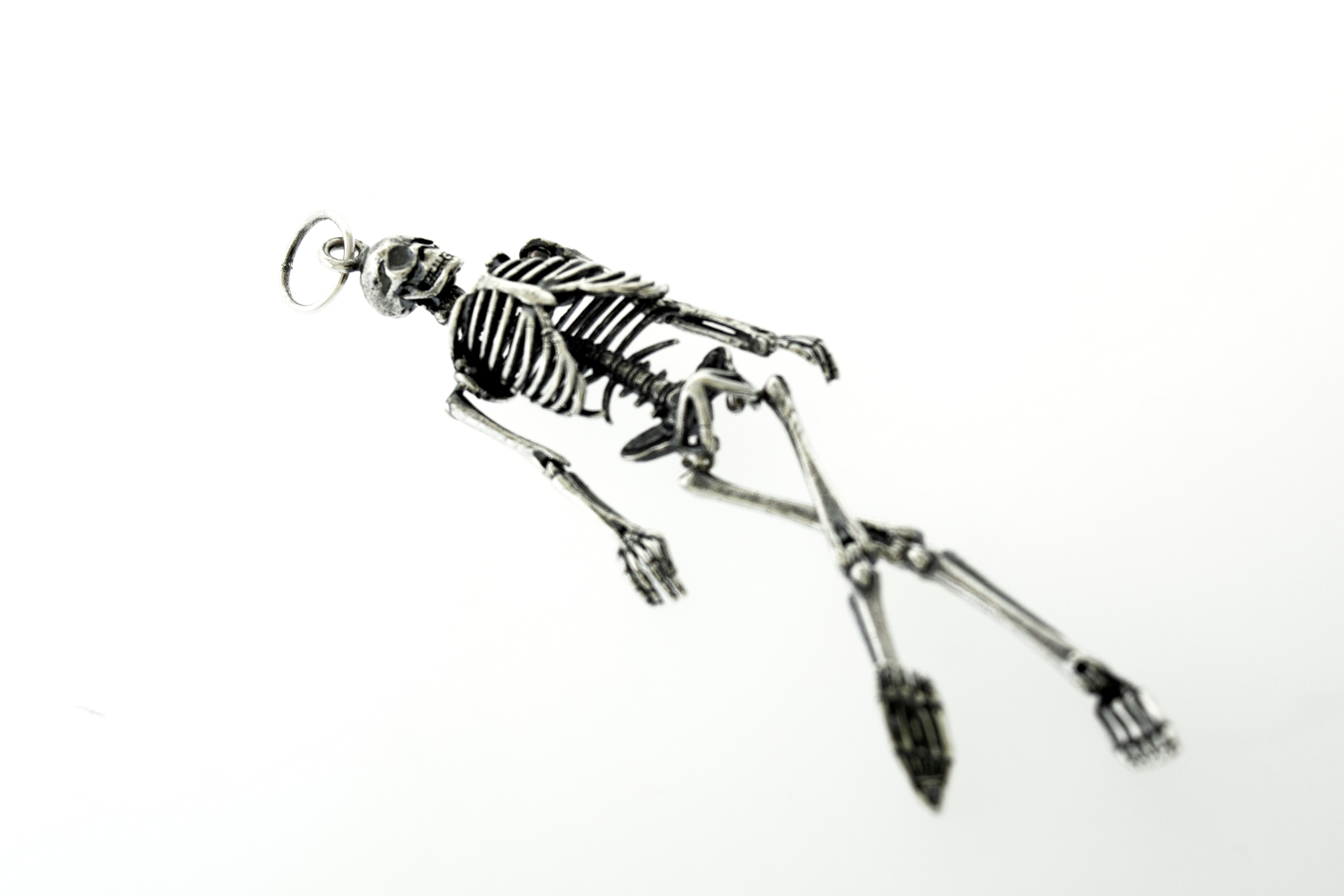 A statement piece - the Super Silver Large Skeleton Pendant hanging from a chain on a white surface, adding style to any outfit.