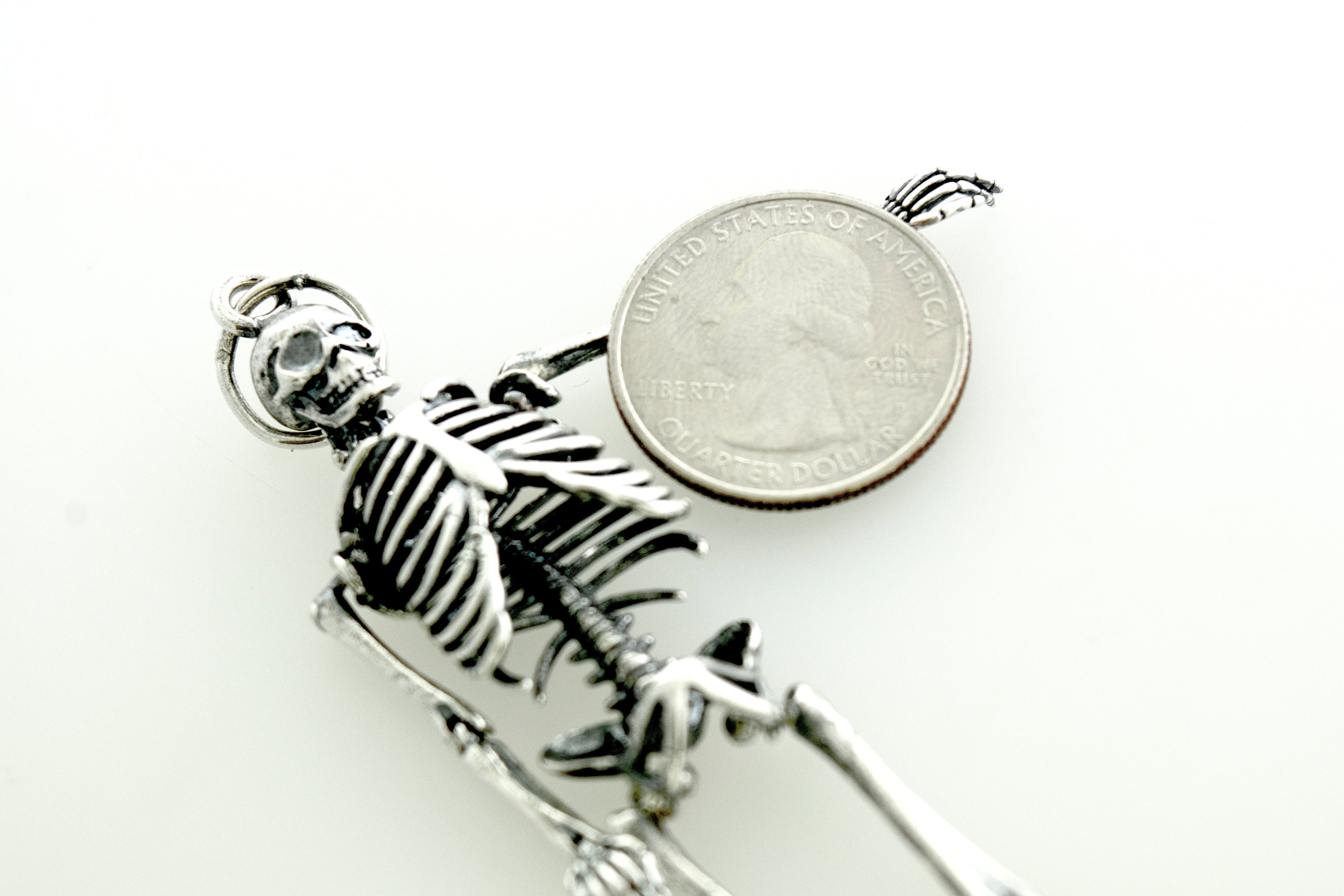 A stylish Large Skeleton Pendant by Super Silver, resting on top of a coin, creating a stunning statement piece.