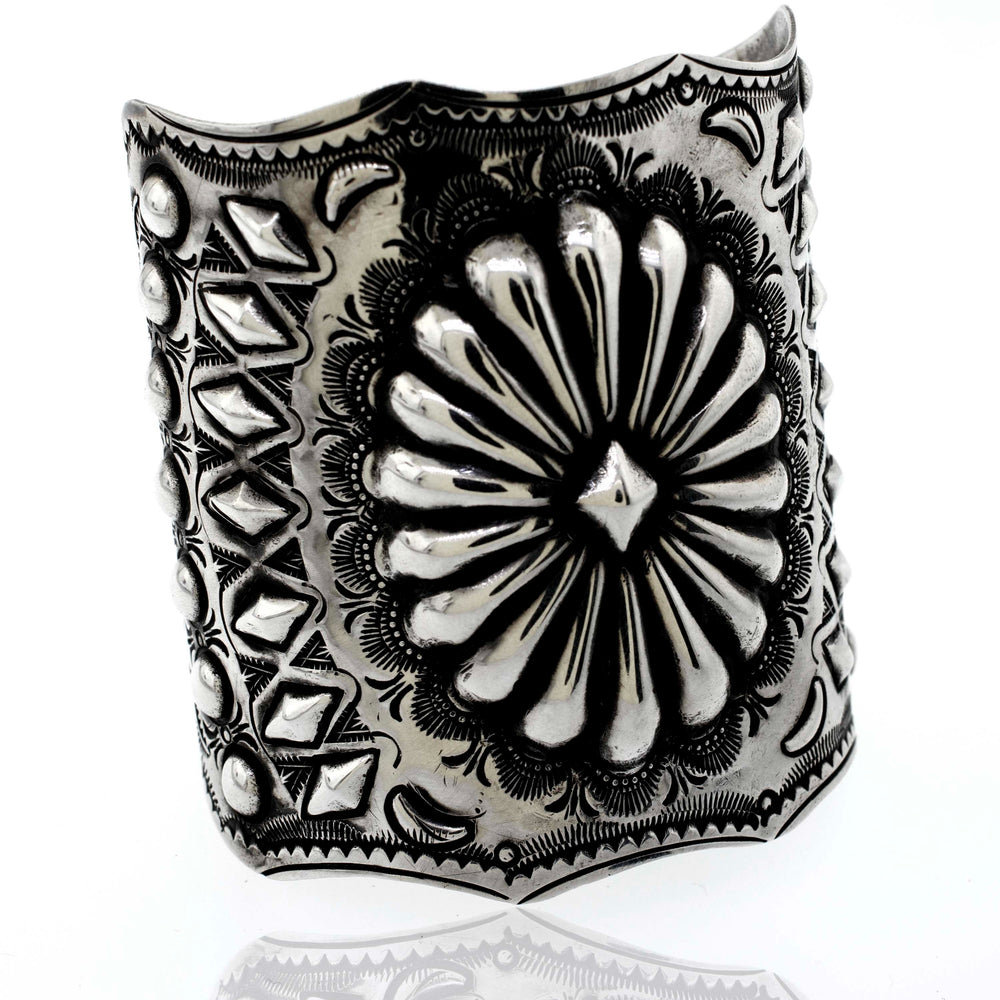 A Handcrafted Silver Concho Cuff with intricate floral and geometric designs, reminiscent of Native American artistry.