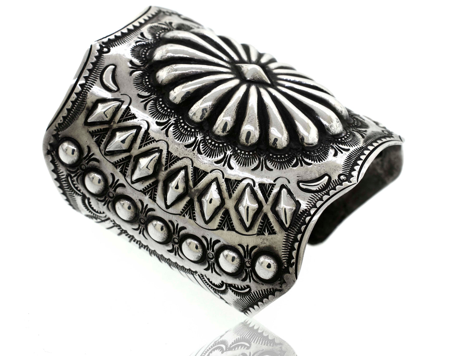 
                  
                    *Handcrafted Silver Concho Cuff* with intricate engraved patterns, including geometric shapes, floral motifs, and rows of raised dot accents, reminiscent of a traditional Native American concho cuff.
                  
                