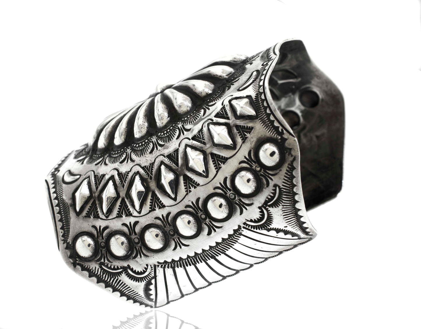 A Handcrafted Silver Concho Cuff featuring intricate engraved patterns and detailing, displayed on a white background.