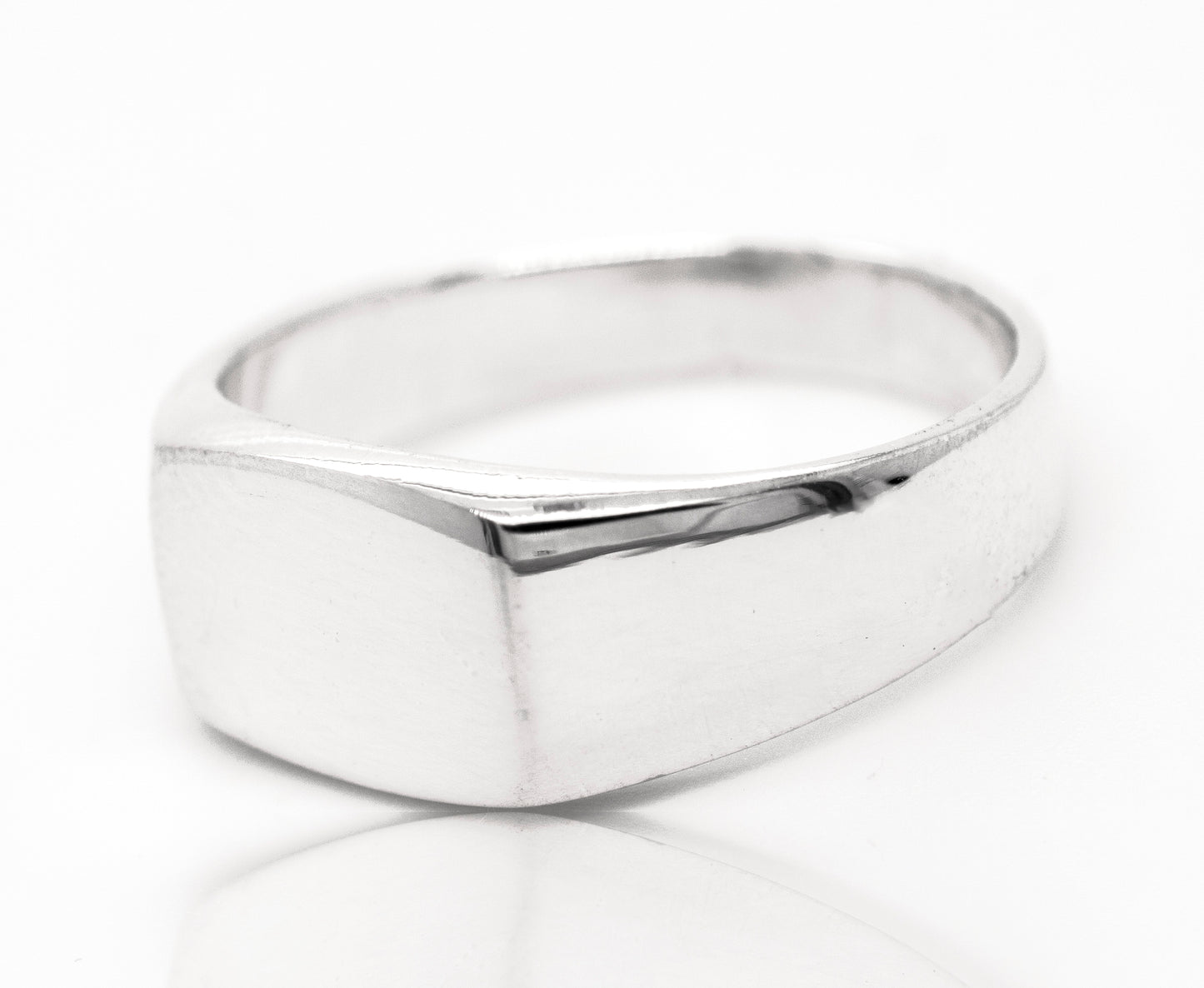 A sterling silver rectangular signet ring with engraving on a white surface.