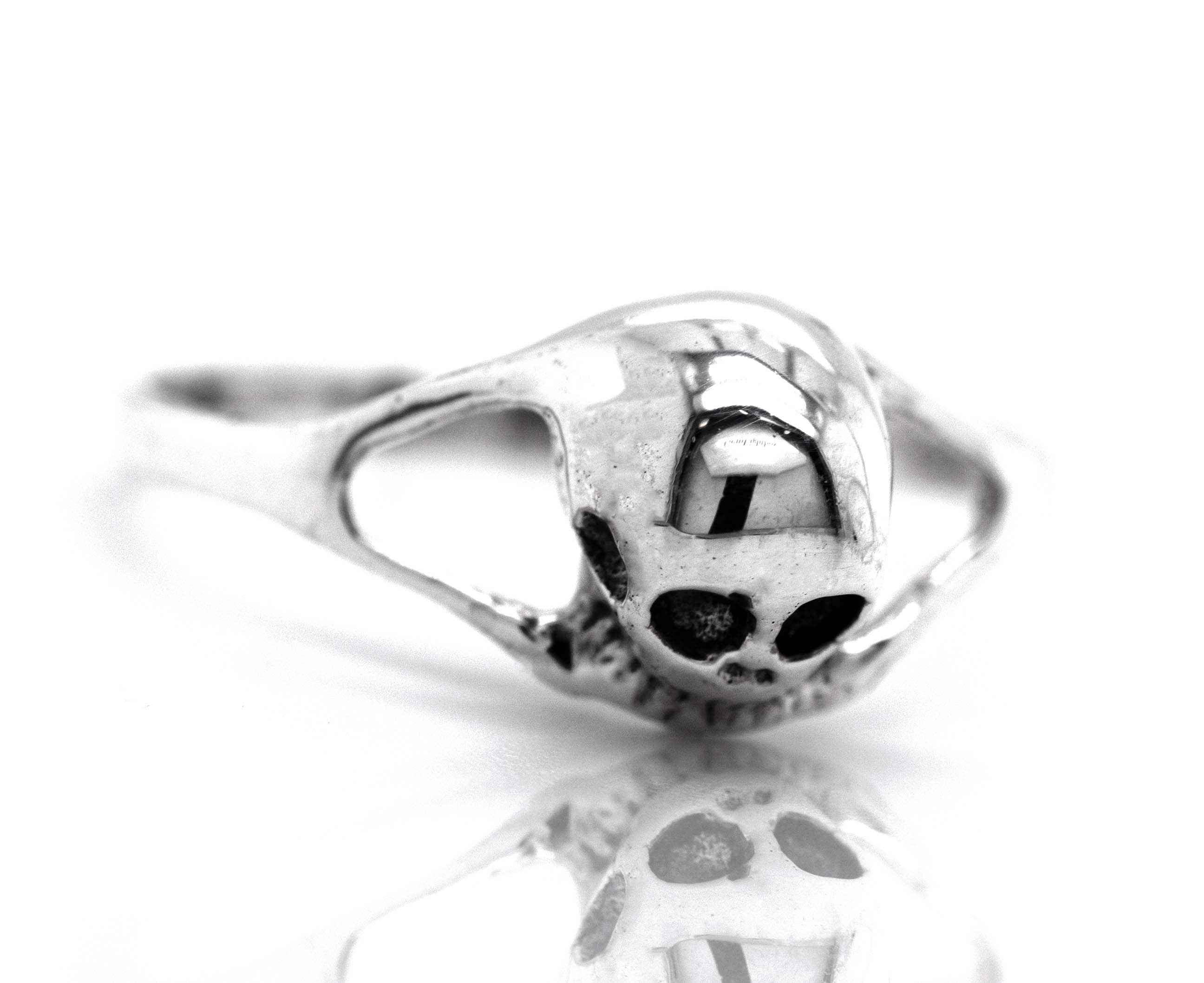 A dainty skull ring on a white surface.