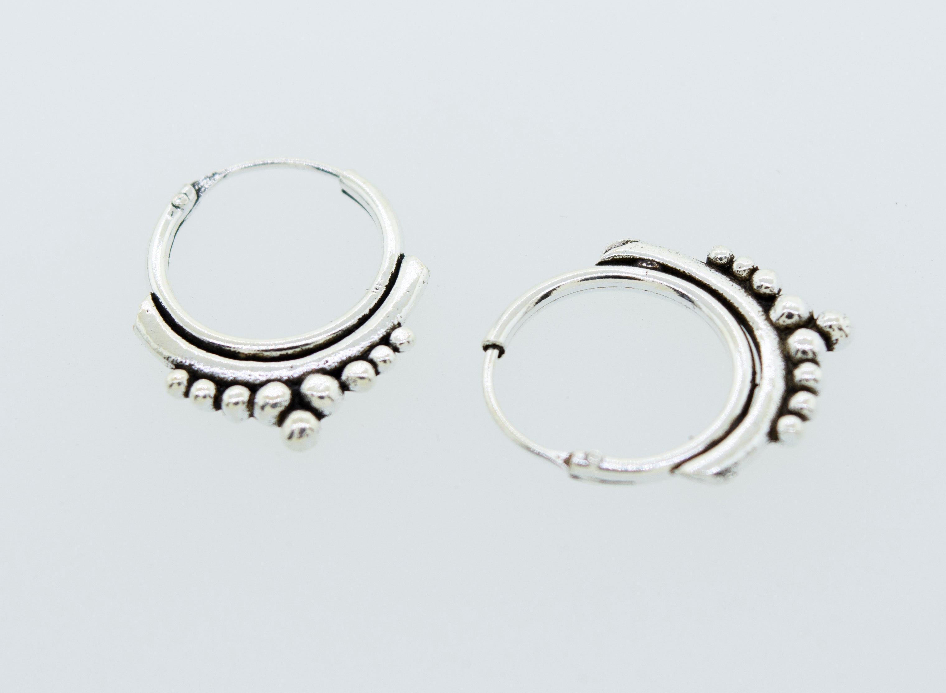 A pair of Super Silver Small Freestyle Ball Hoop earrings on a white surface.