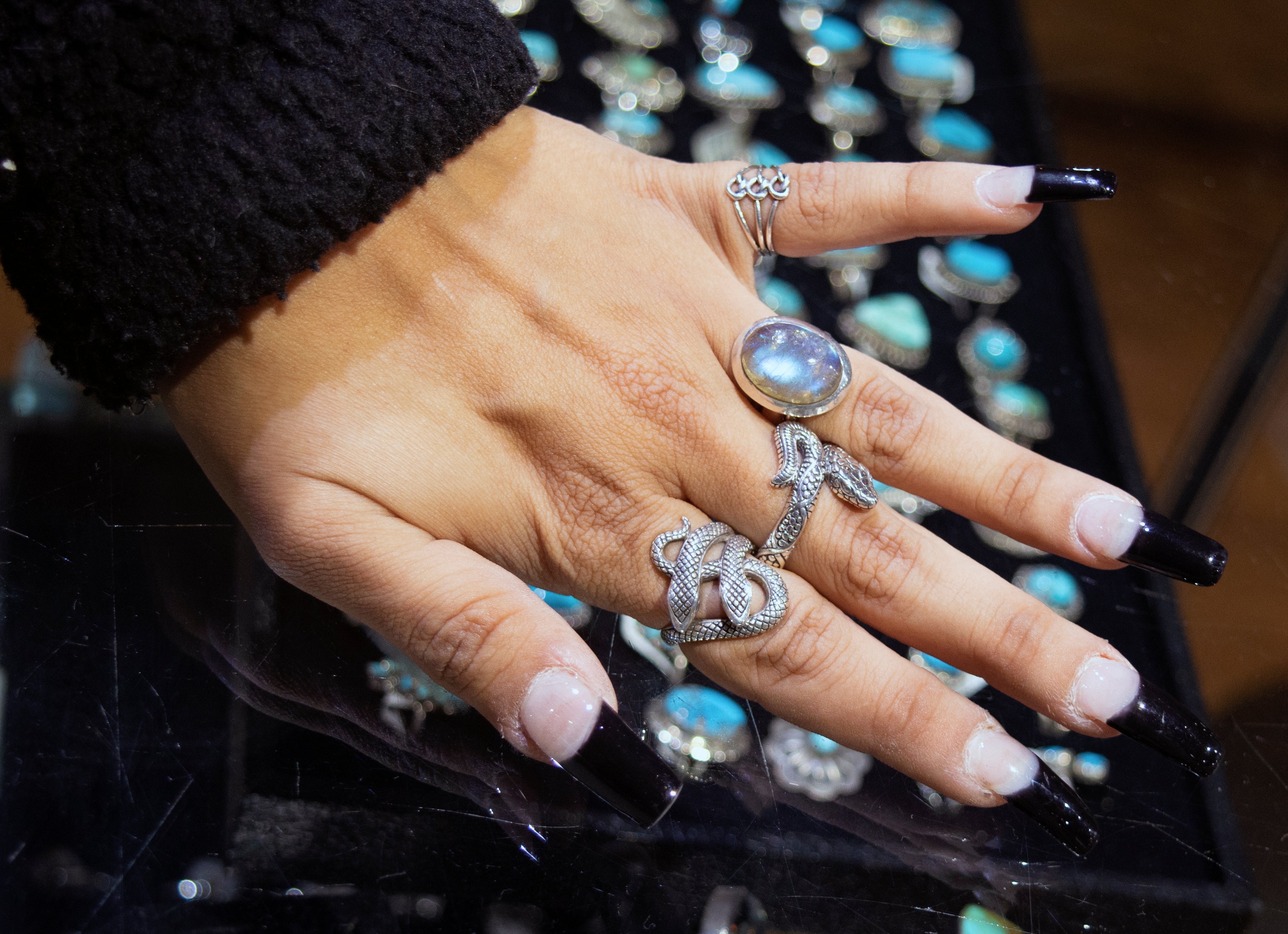 A handcrafted Super Silver Double Headed Snake Ring adorns the graceful woman's hand, adding a touch of elegance and intrigue.