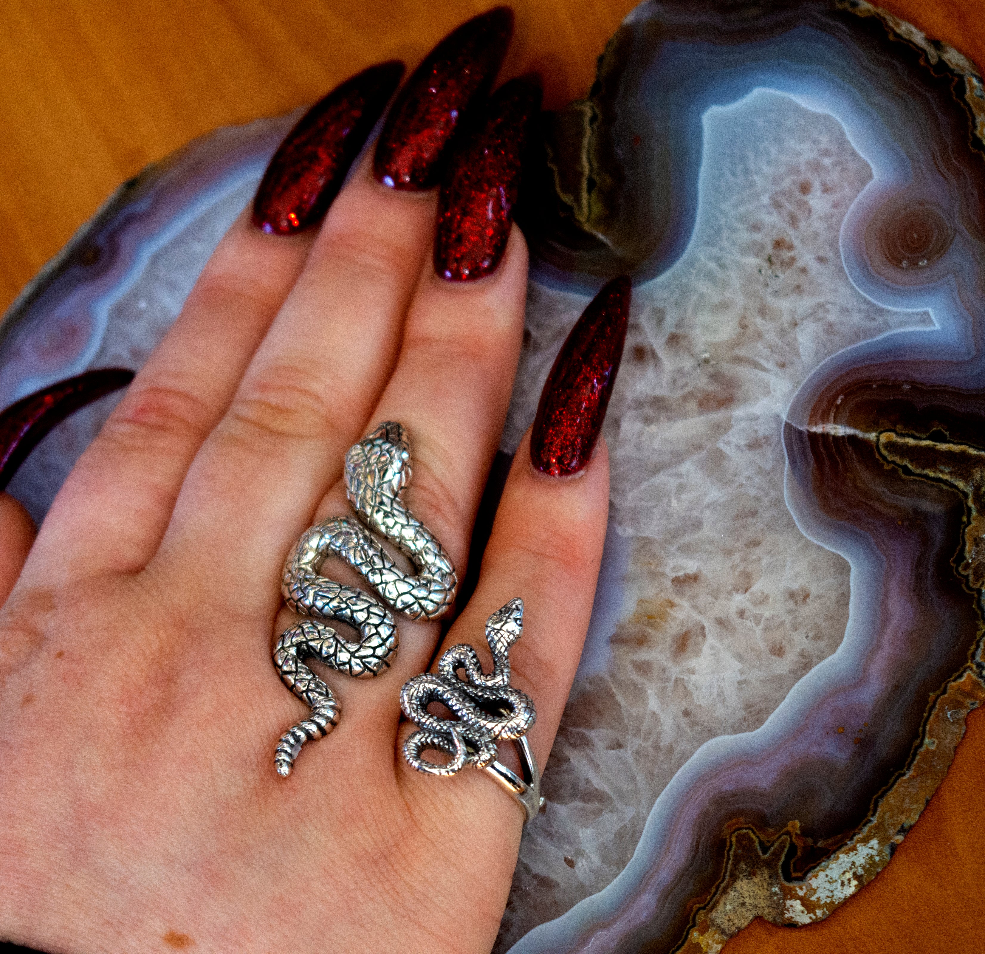 The Long Alluring Snake Ring delicately adorns a woman's hand, resting gracefully atop an exquisite agate.