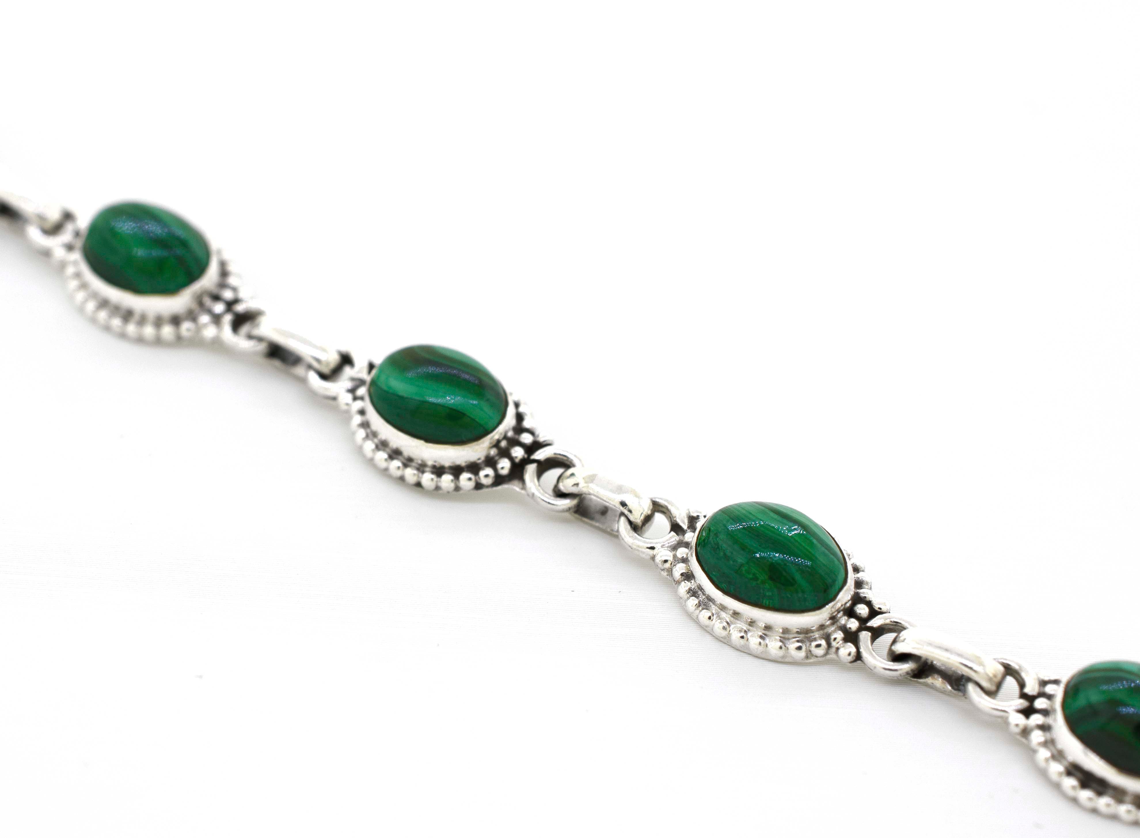 A Super Silver Oval Gemstone Bracelet With Ball Border with green gemstones on it.