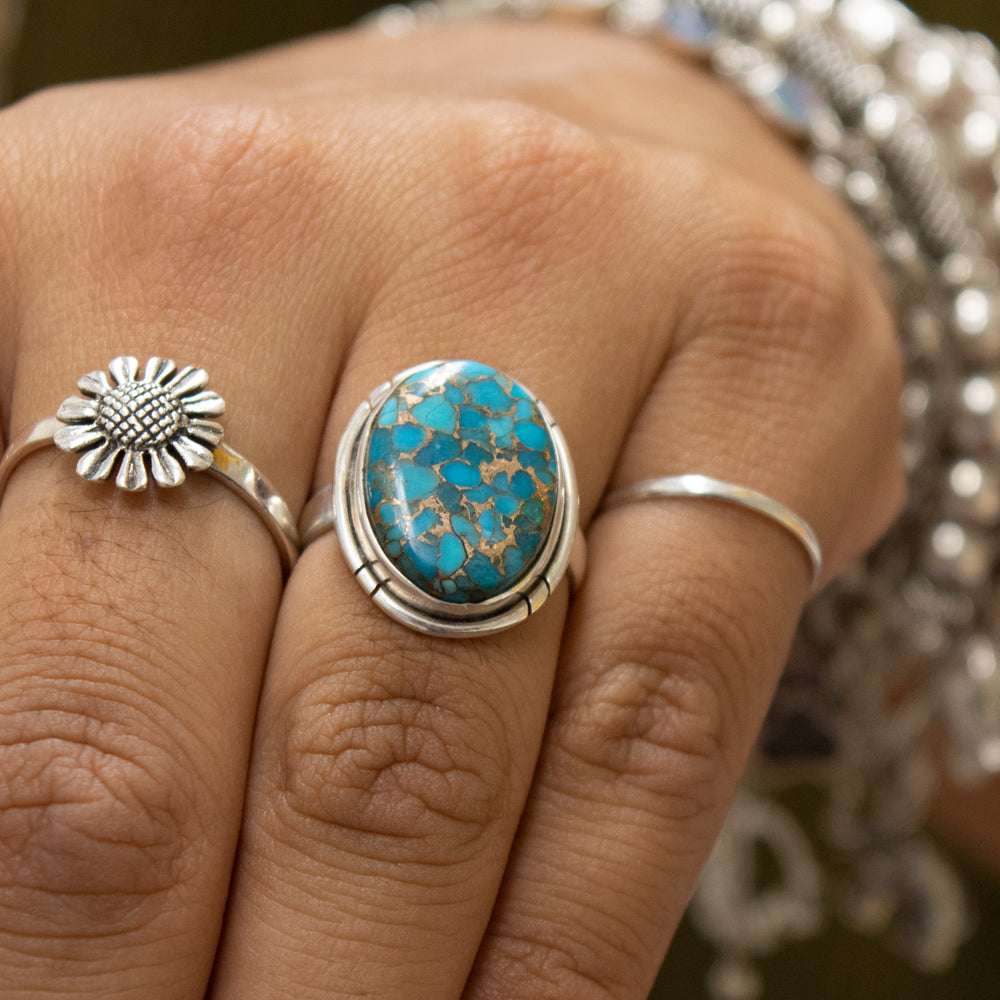 A woman's hand adorned with a beautiful Super Silver ring featuring an exquisite oval Natural Blue Copper Turquoise stone.