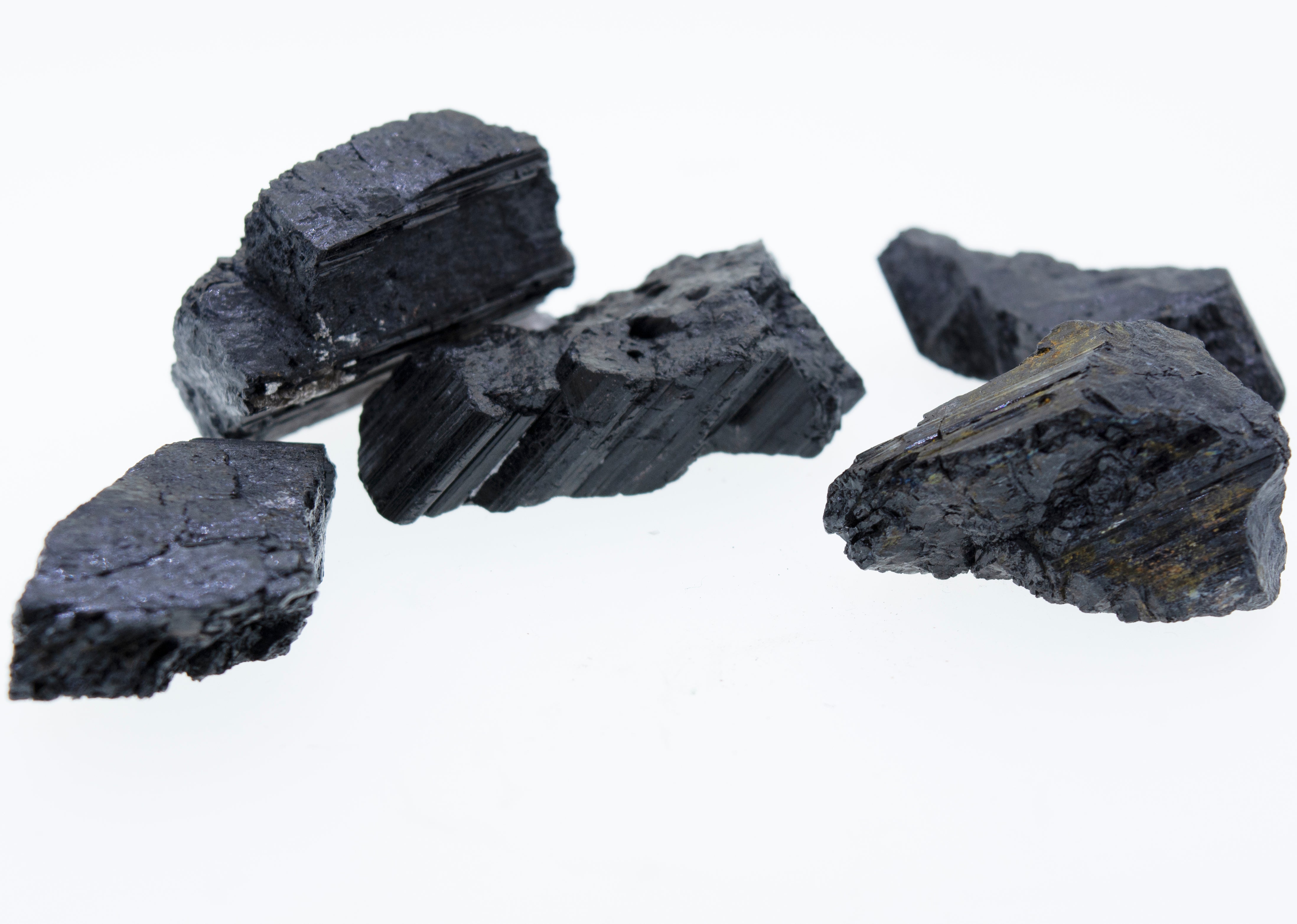 A stack of Rough Black Tourmaline Crystals on a white background.