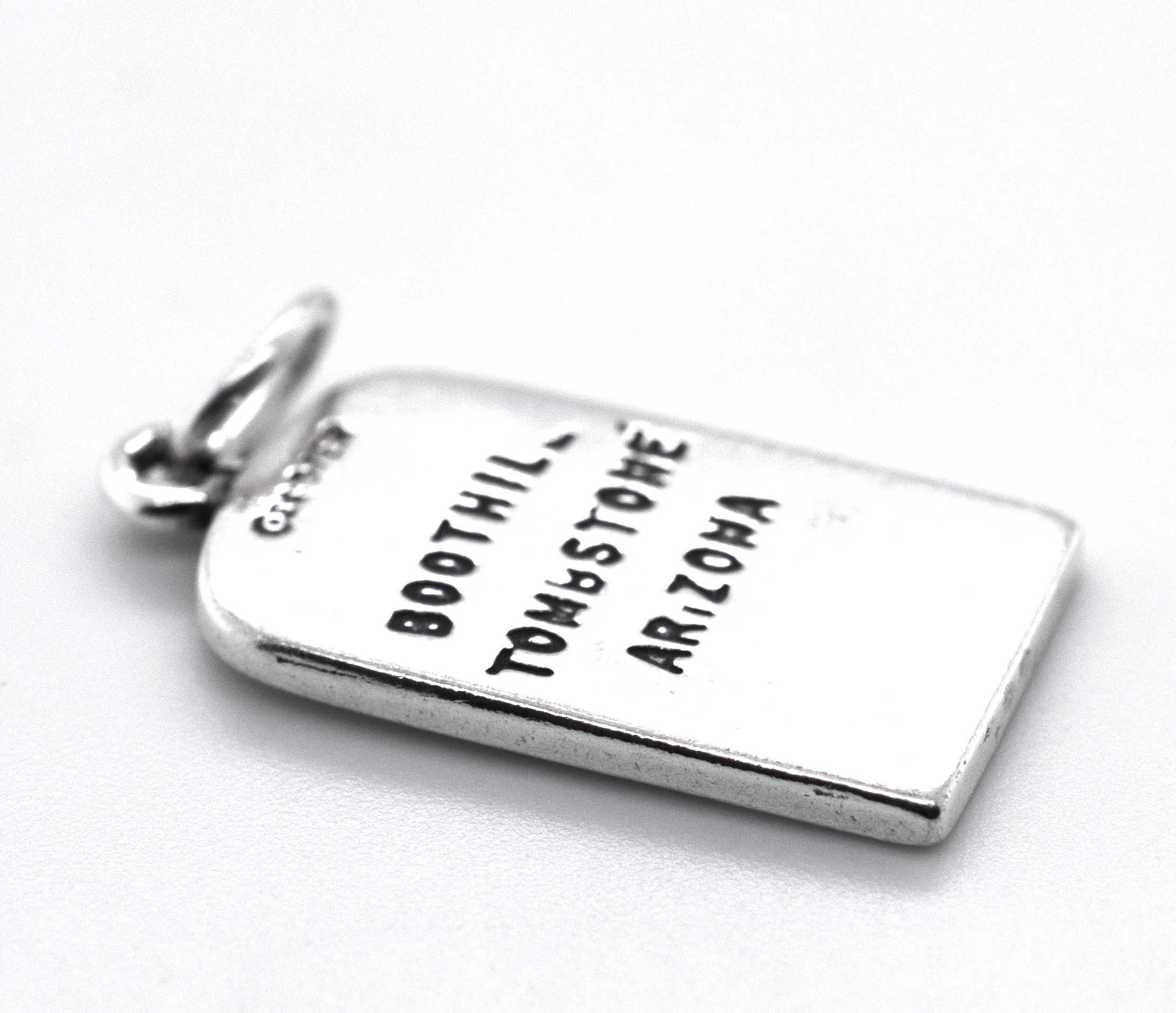 A silver charm with the words "Lester Moore Gravestone Charm" and "Super Silver" on it.