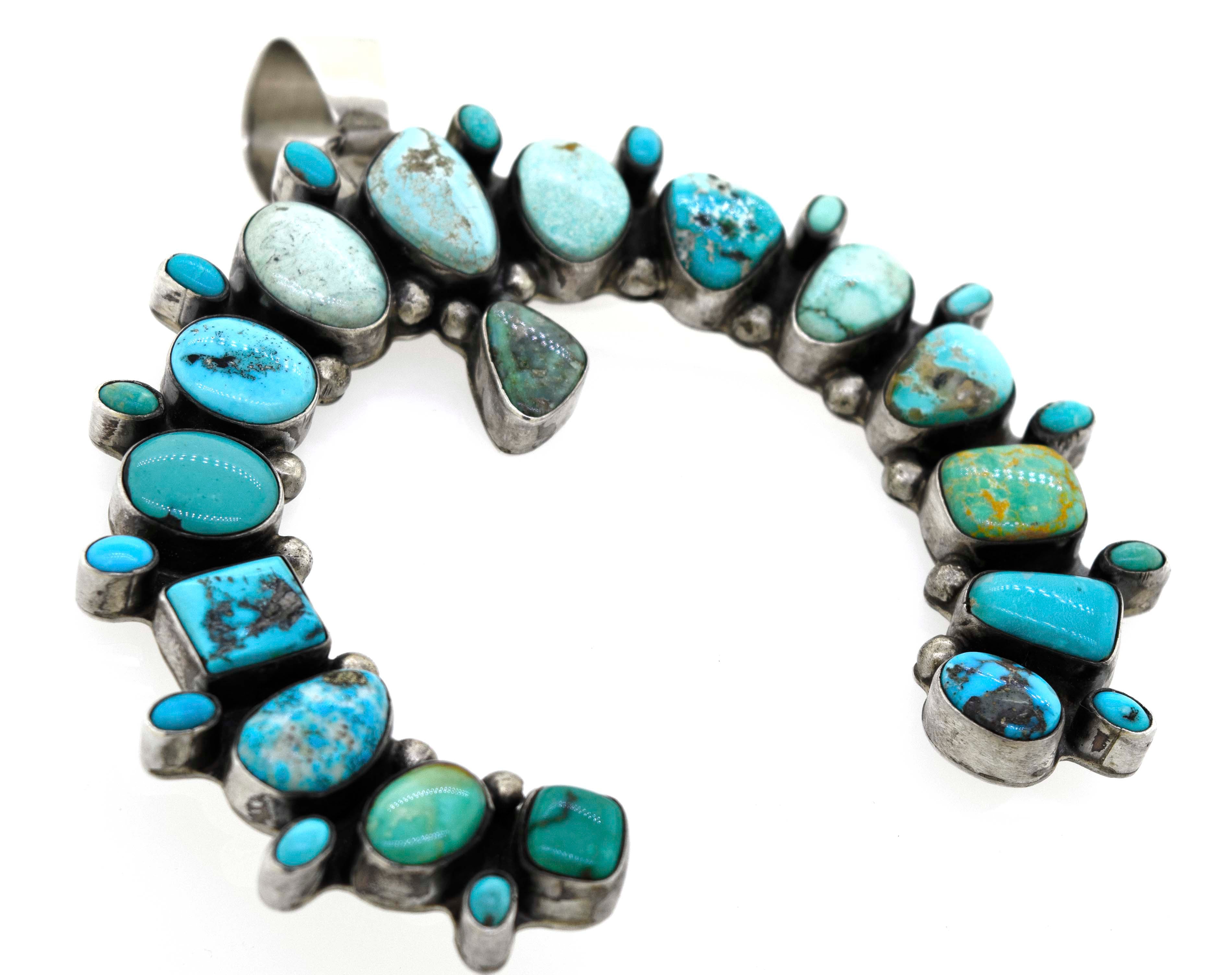 A Super Silver Stunning Handcrafted Naja Pendant necklace with turquoise stones on it.