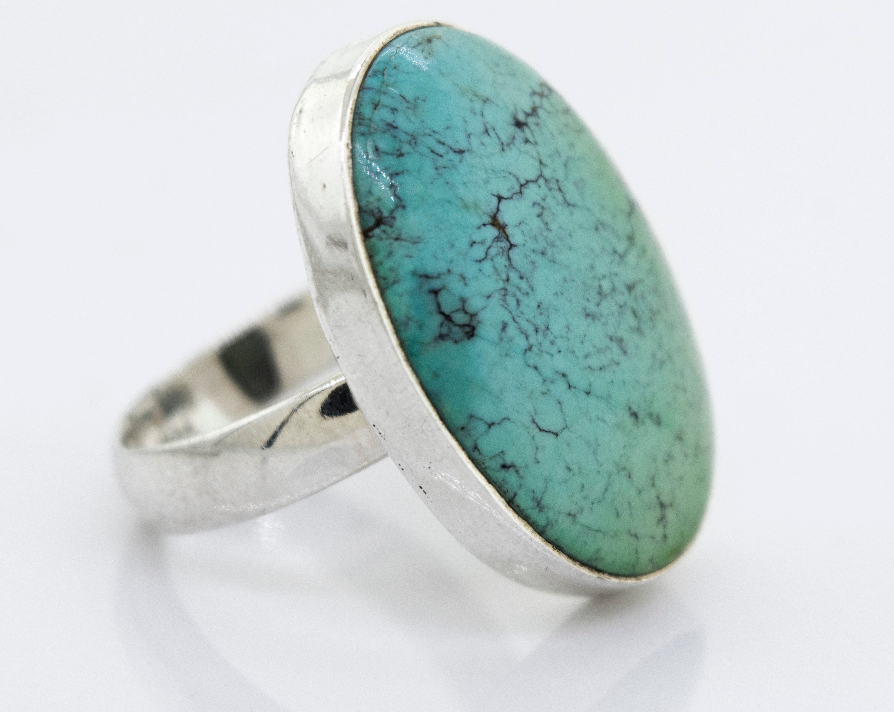 A unique Super Silver Oval Natural Turquoise Ring with a sterling silver setting on a white surface.
