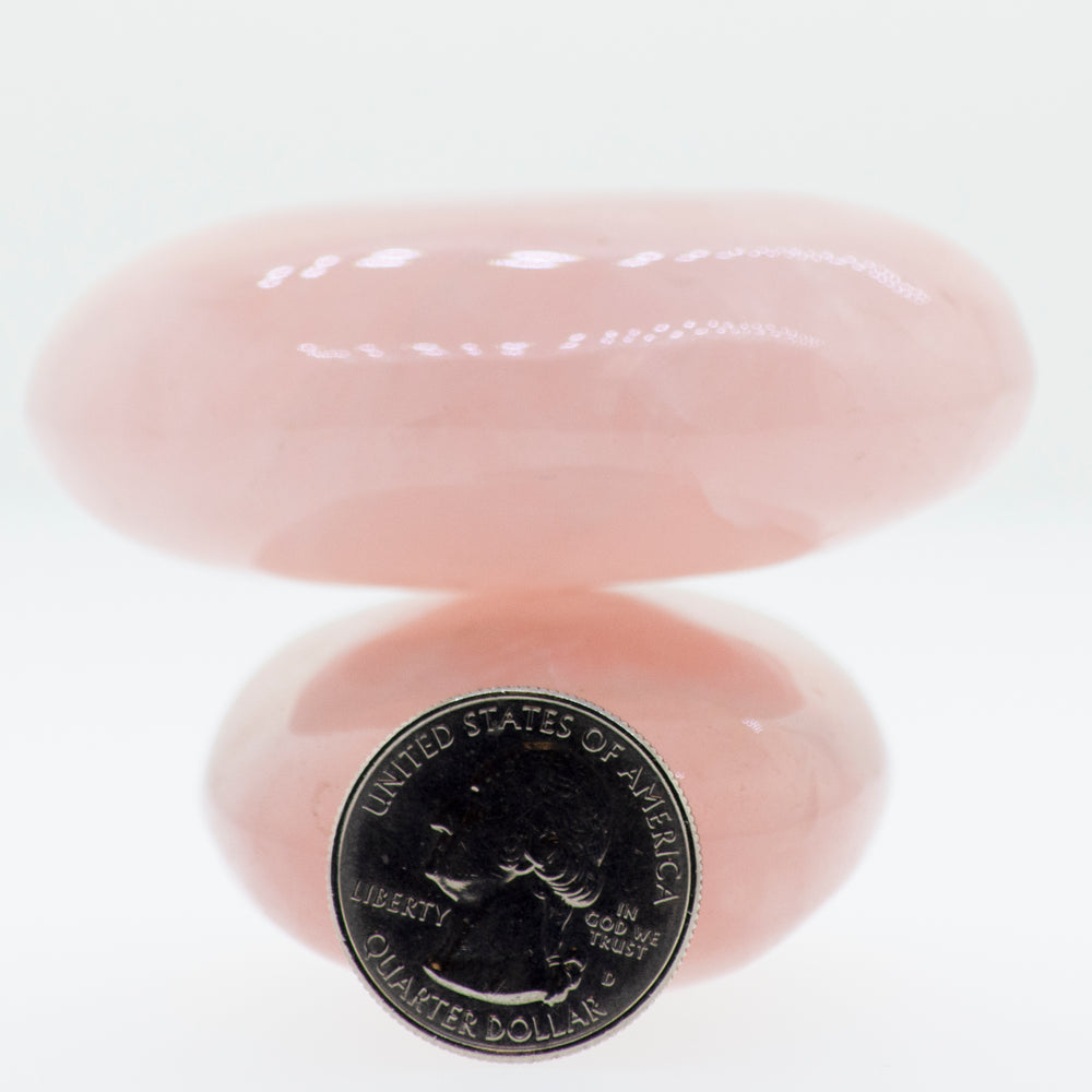 A Rose Quartz Worry Stone with a pink stone on top of it.