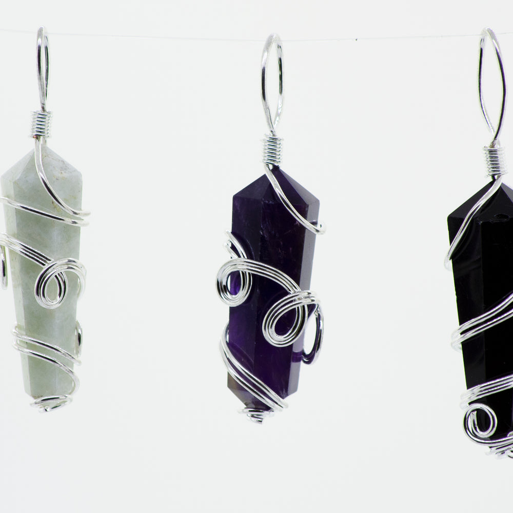 Three Super Silver wire-wrapped stone pendants hanging from a string.