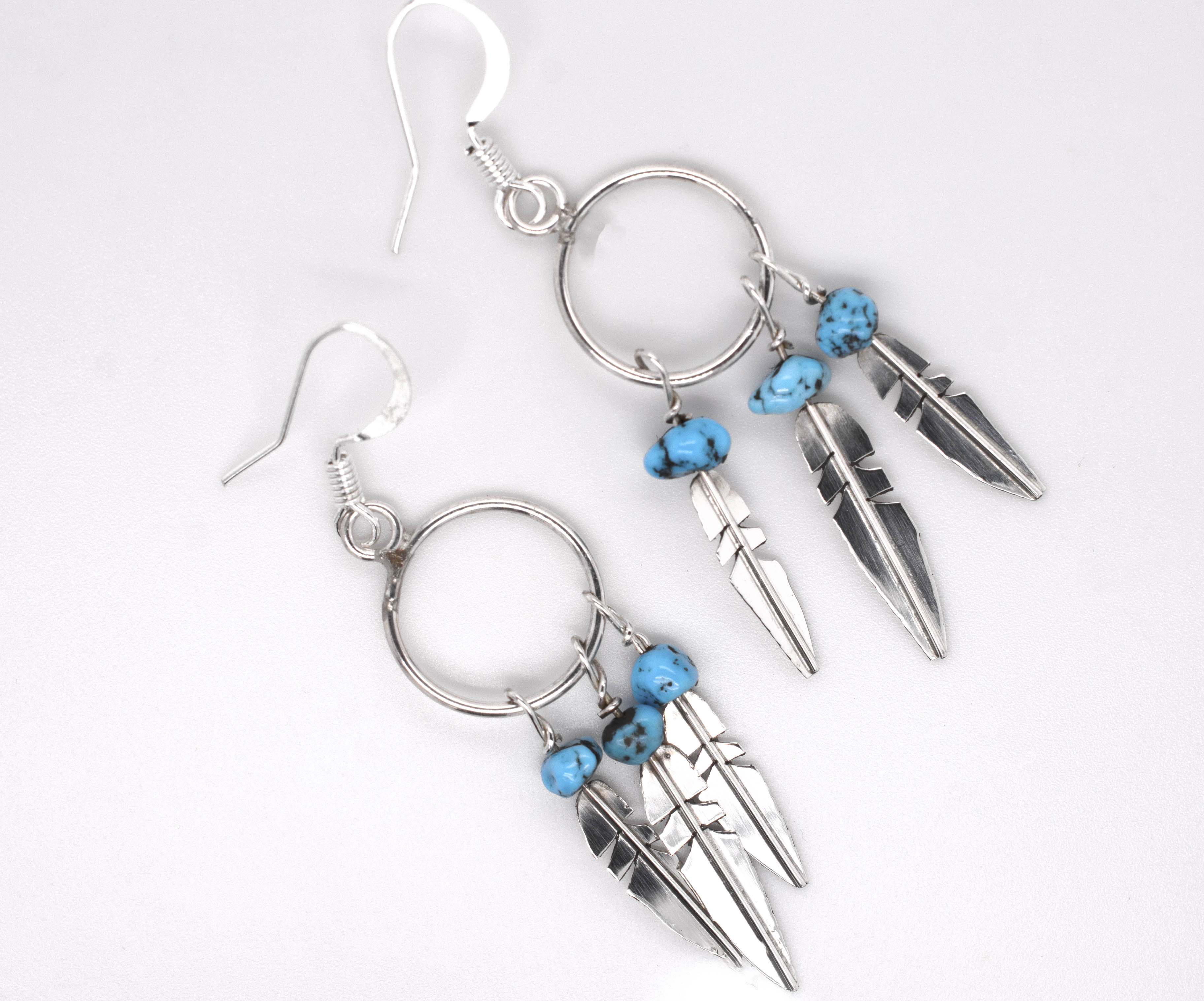 A pair of Super Silver Enchanting Zuni Feather Earrings with Coral or Turquoise beads.