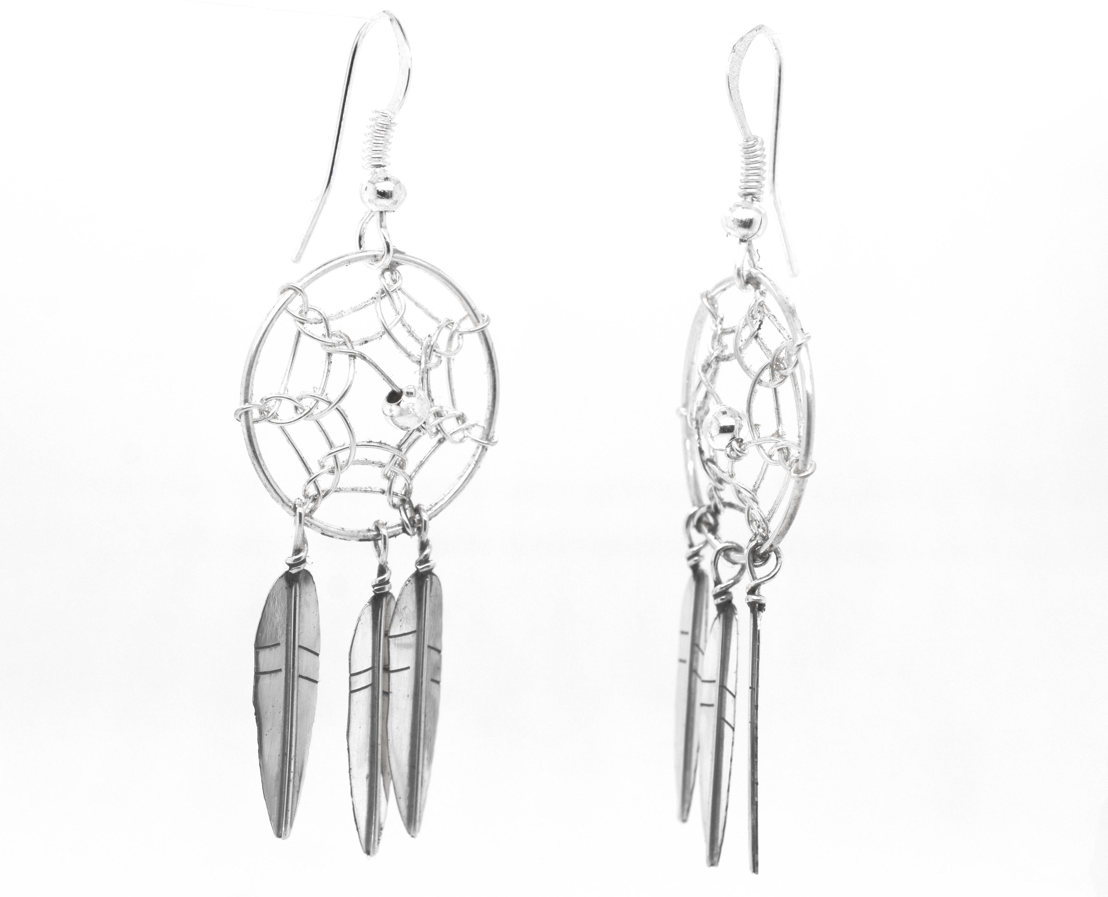 A pair of stunning Zuni Dreamcatcher earrings by Super Silver with feathers. These Zuni dreamcatcher earrings are beautifully adorned with silver feathers, creating a boho charm effect.