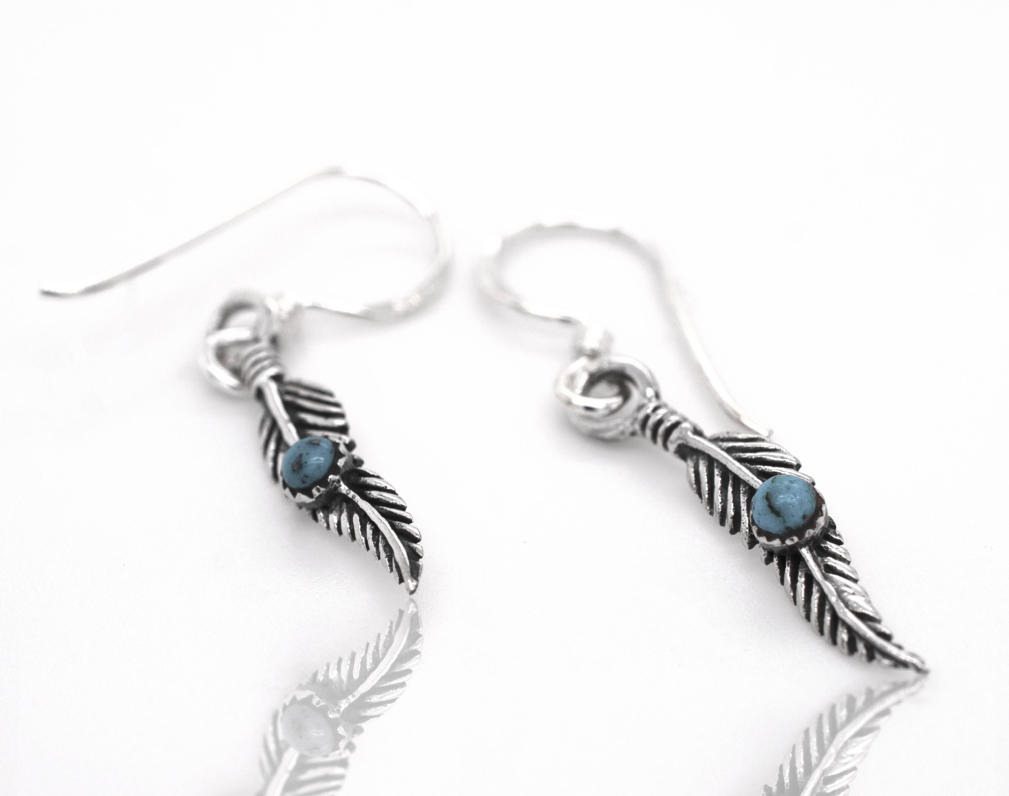 Super Silver's Delicate Feather Earrings adorned with vibrant turquoise stones.