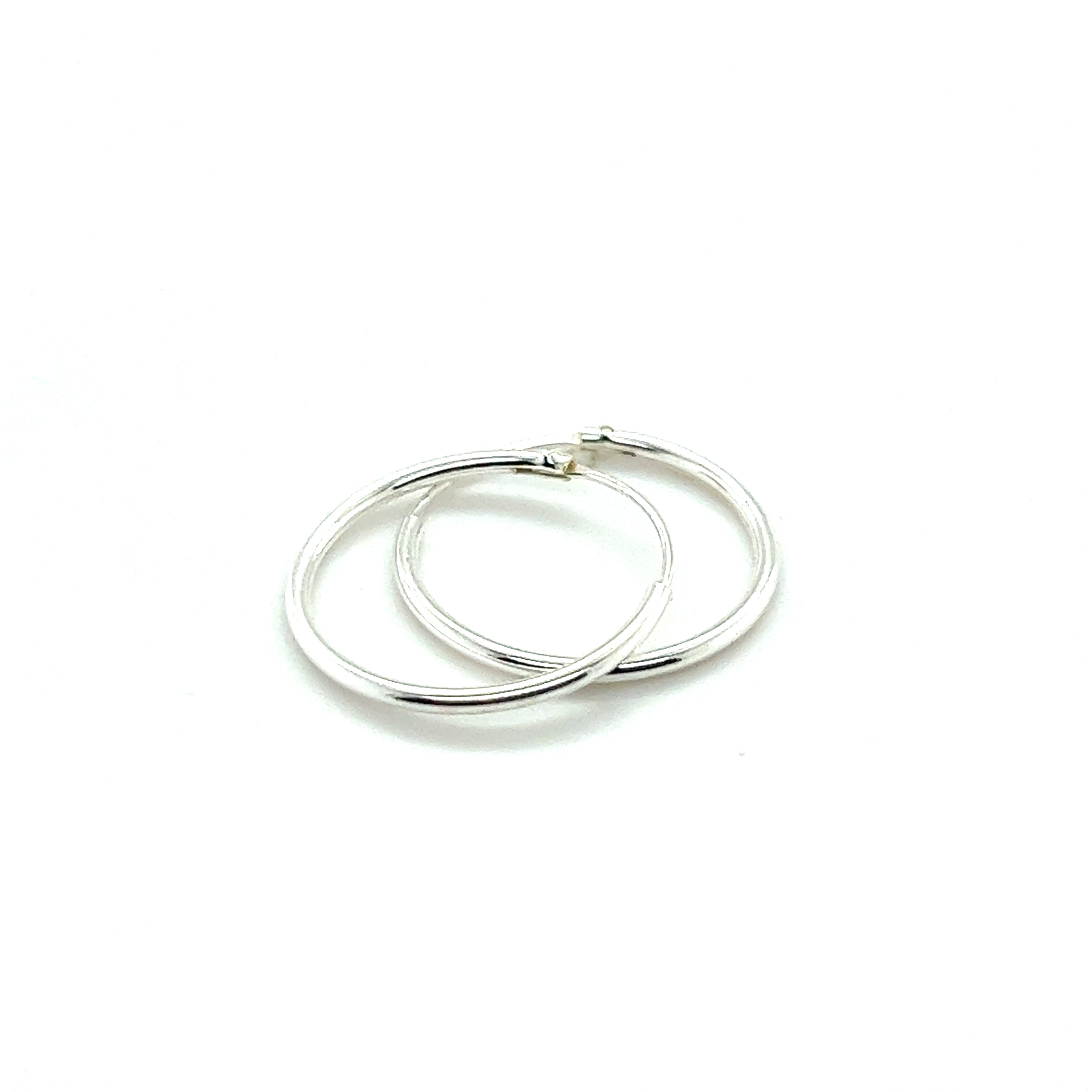 The 1.2mm Infinity Hoops, crafted from .925 Sterling Silver, lie elegantly on a white background, showcasing their timeless hoop design.